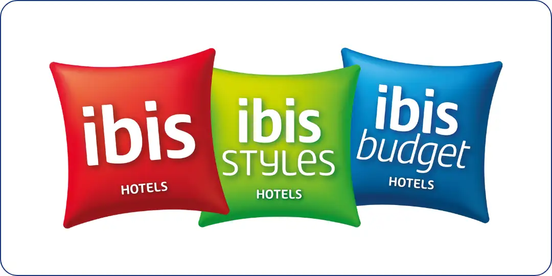 Drei Kissen mit den weißen Schriftzügen 'ibis', 'ibis Styles' und 'ibis budget', die verschiedene Hotelmarken repräsentieren