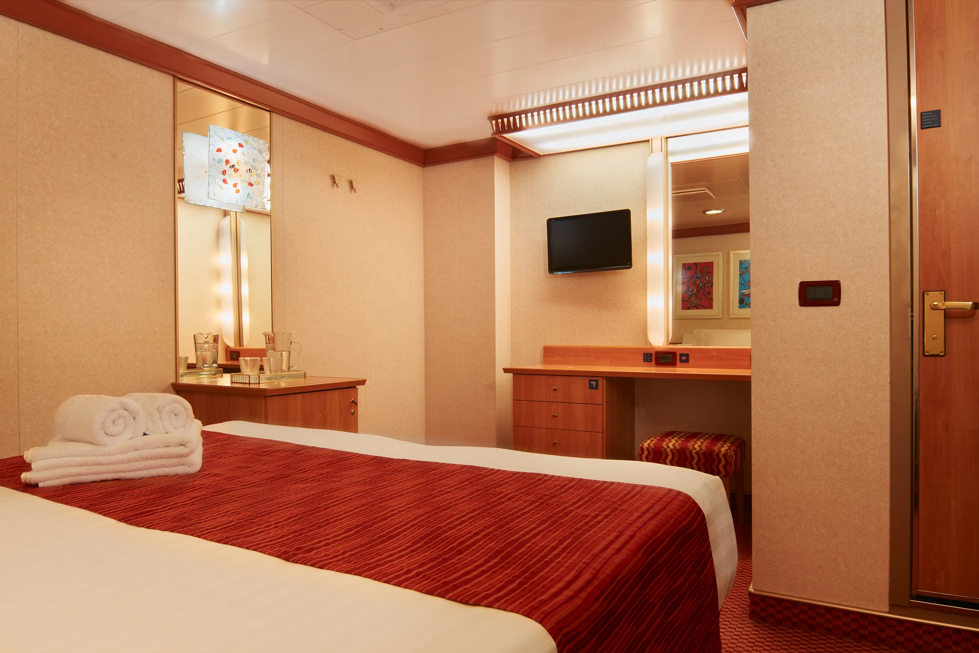 Modernes Hotelzimmer mit rotem Bettüberwurf und stilvollem Mobiliar.