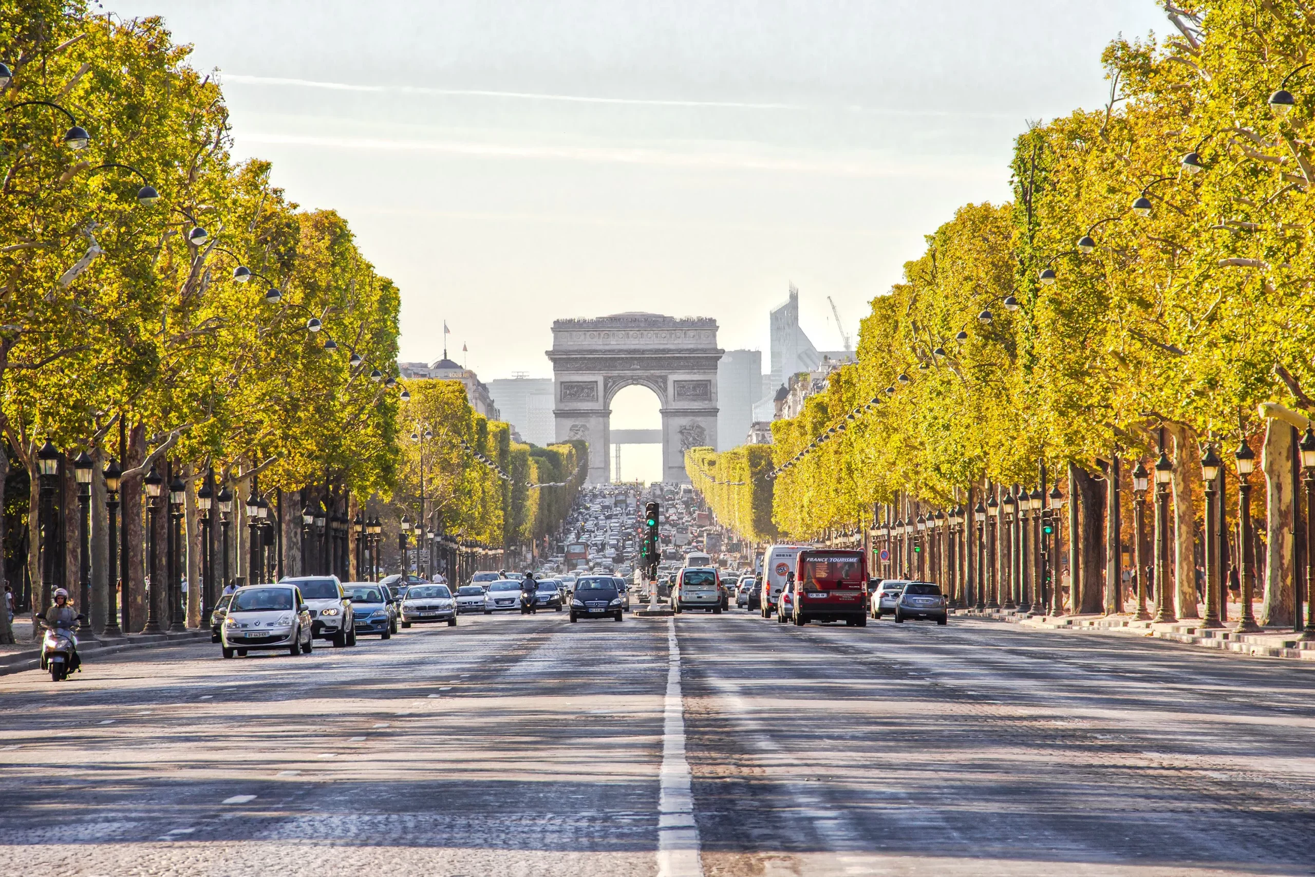 Die belebte Champs Elysees mit dem Triumphbogen im Hintergrund bei Sonnenschein.