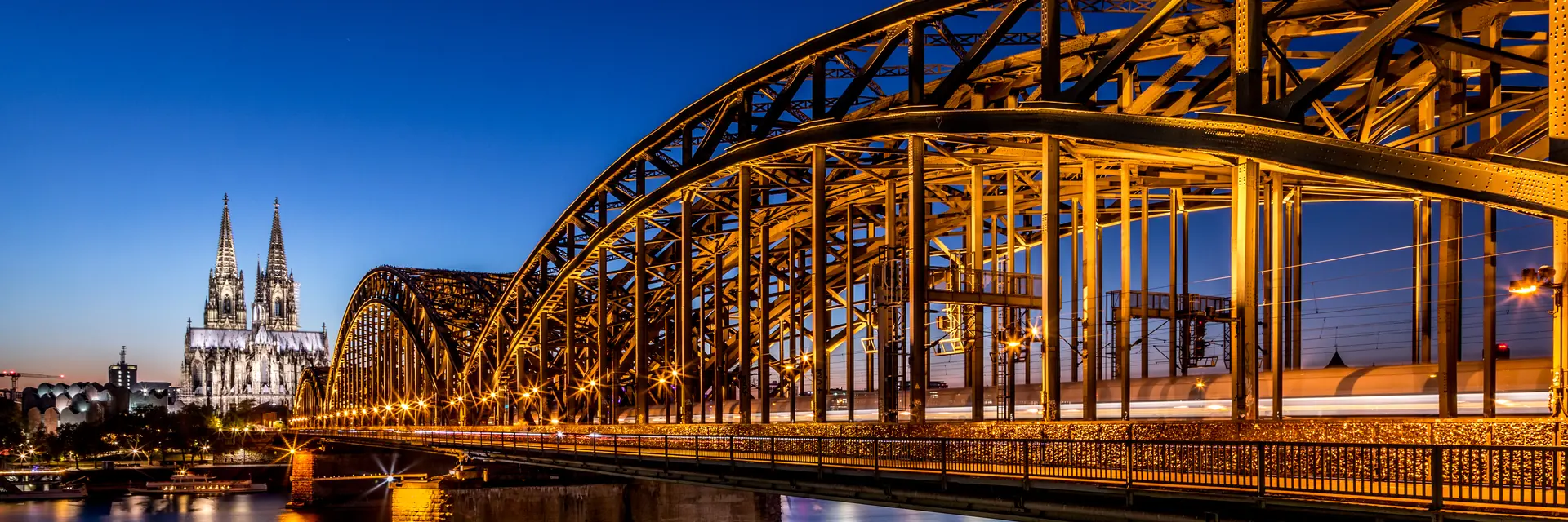 Panorama von der beleuchteten Hohenzollernbrücke in Köln am Abend
