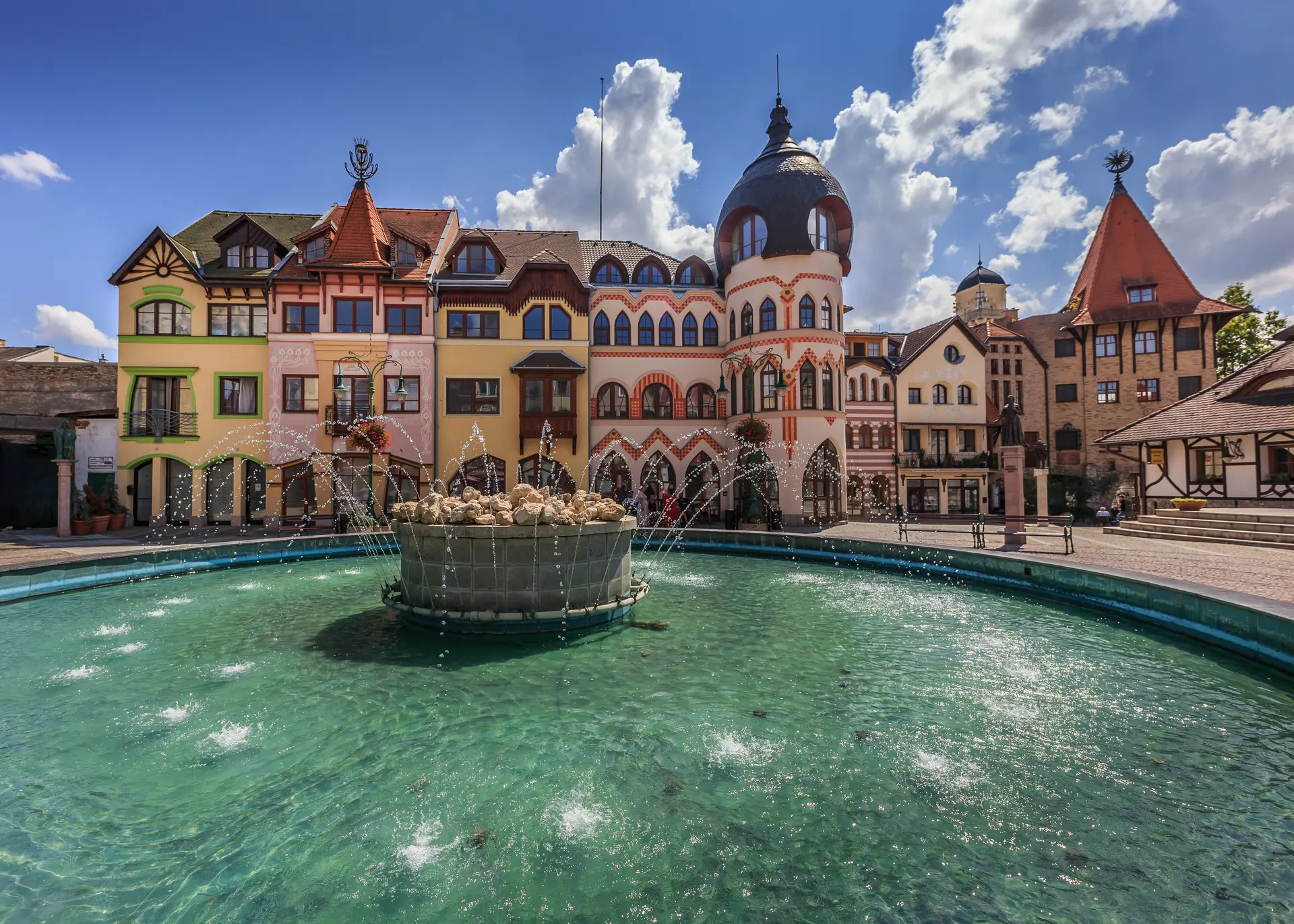 Springbrunnen am Europaplatz mit markanten Häusern in Komárno, Slowakei