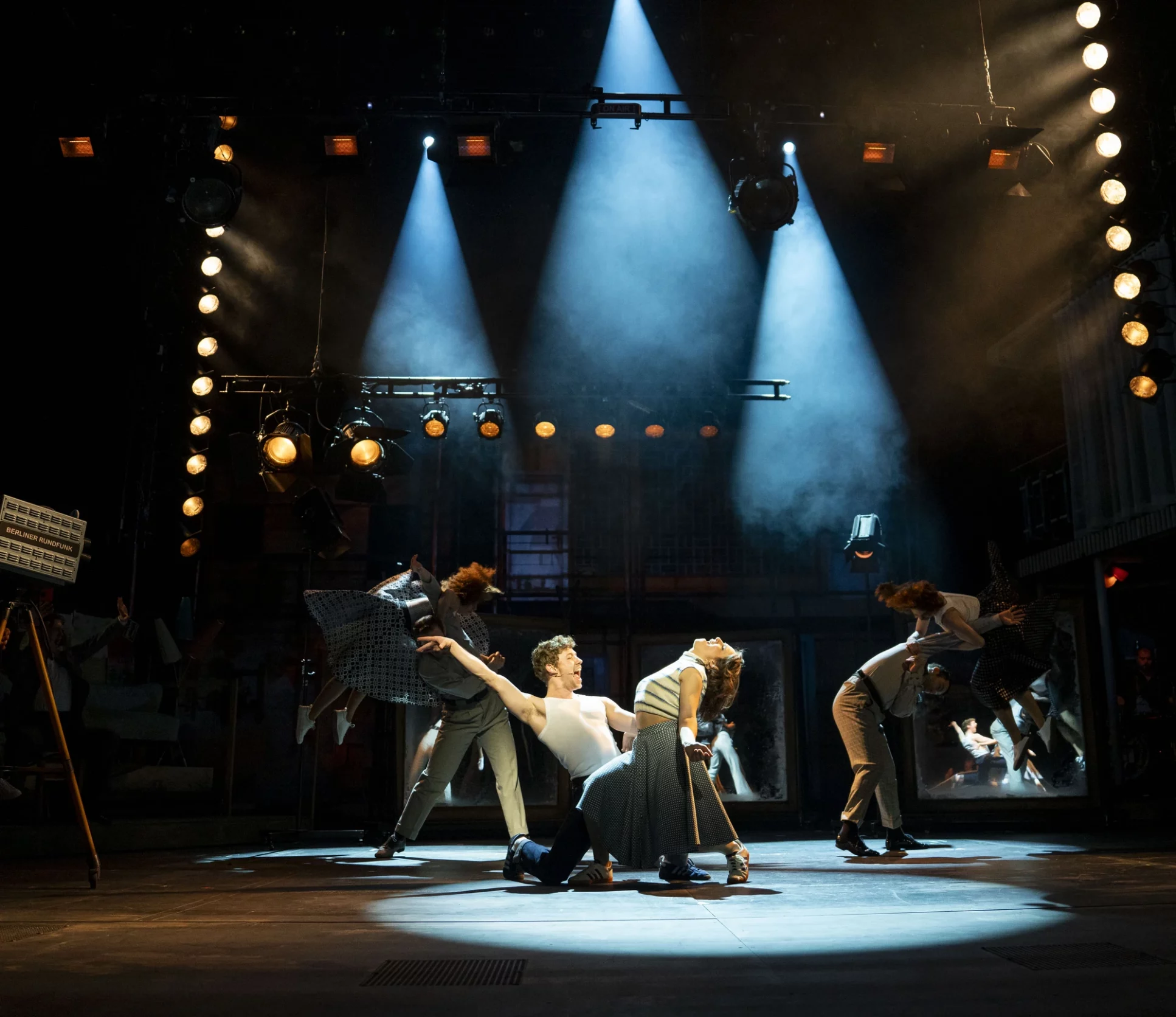Eine moderne Tanzaufführung mit mehreren Tänzern auf einer beleuchteten Bühne.