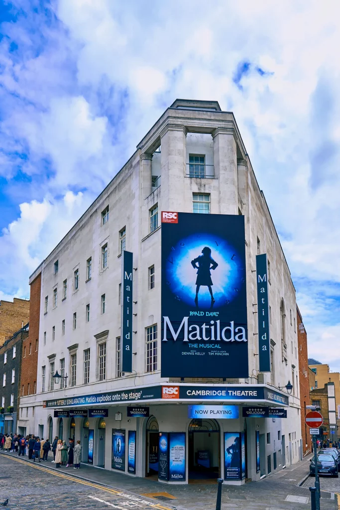 Das Bild zeigt das Cambridge Theatre in London, welches zurzeit das Musical