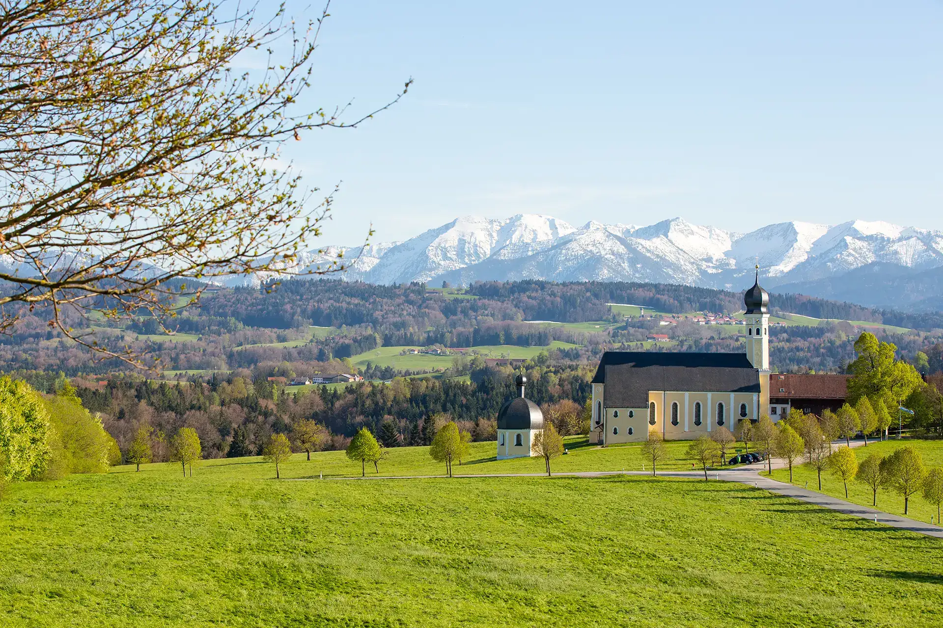 Die Wallfahrtskirche Wilparting mit schneebedeckten Alpen im Hintergrund beim Kurzurlaub Bad Aibling