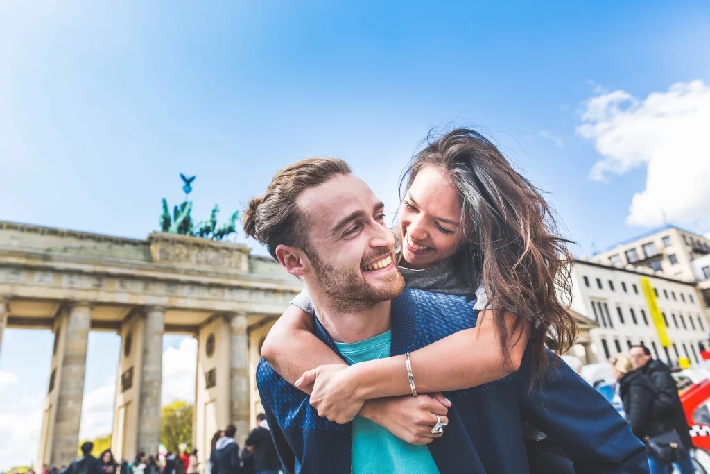 Kurzurlaub in Berlin mit fröhlichem Paar vor dem Brandenburger Tor bei Sonnenschein