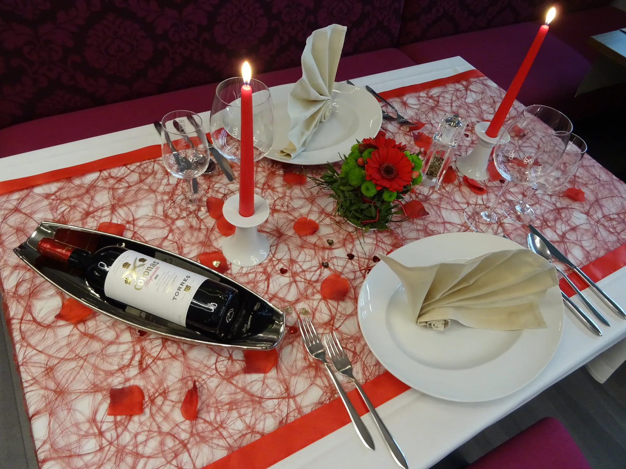 gedeckter Candle-Light-Tisch mit rotem Läufer, roten Kerzen und Rotwein in Timmermans Restaurant in der Sportwelt Radeberg beim Kurzurlaub Sachsen