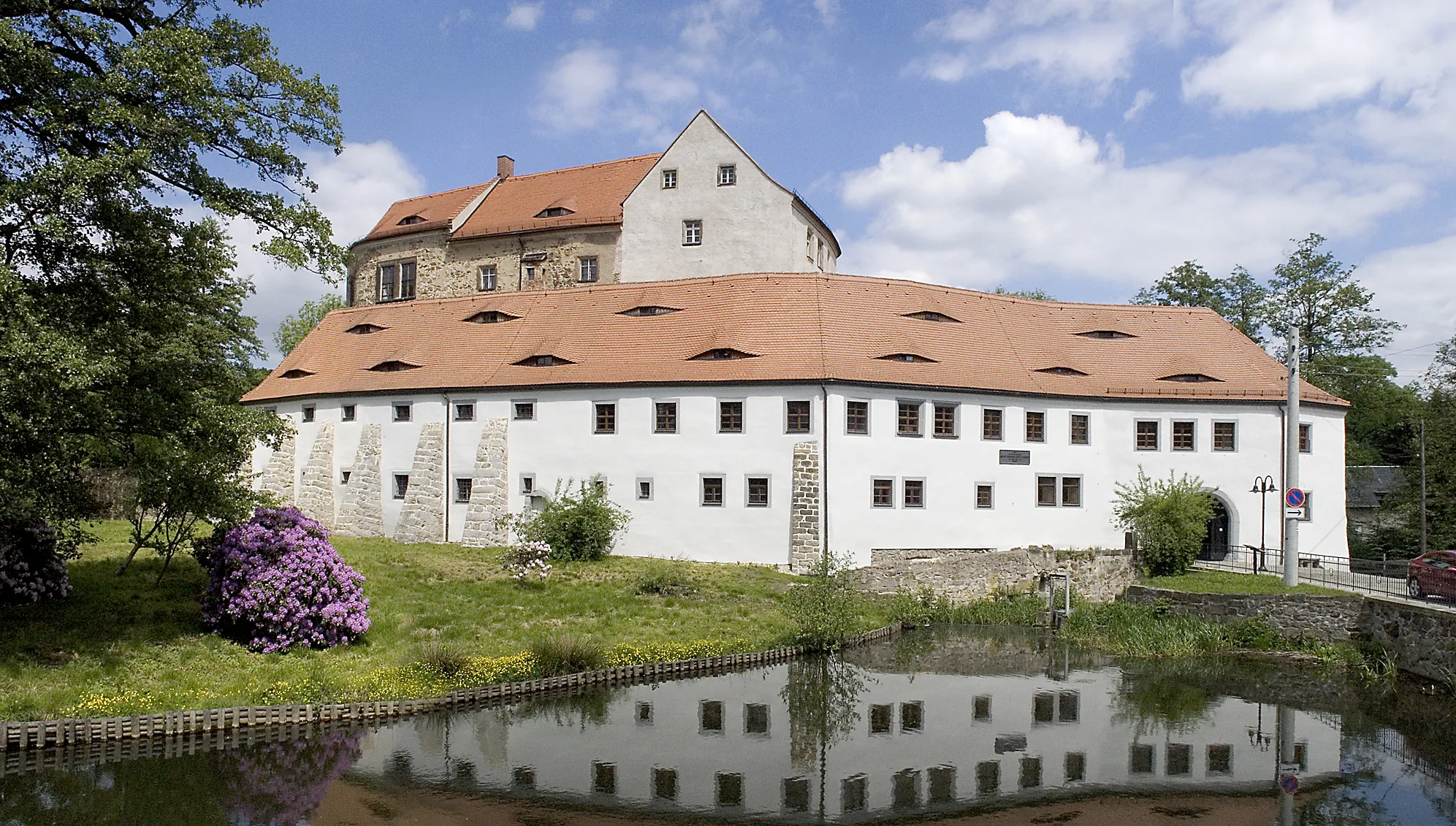 Aussenansicht vom Schloß Klippenstein mit See und blühenden Flieder im Vordergrund in Radeberg beim Kurzurlaub Sachsen