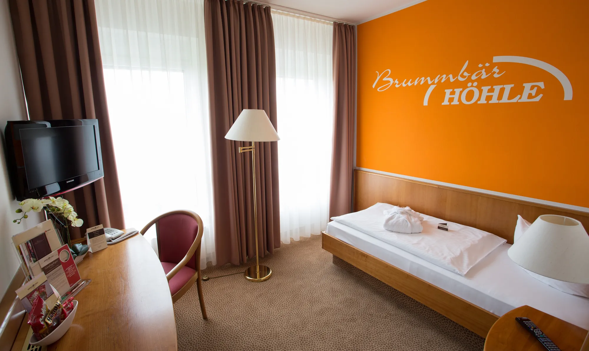 Einzelzimmer mit orangener Wand mit Aufschrift 