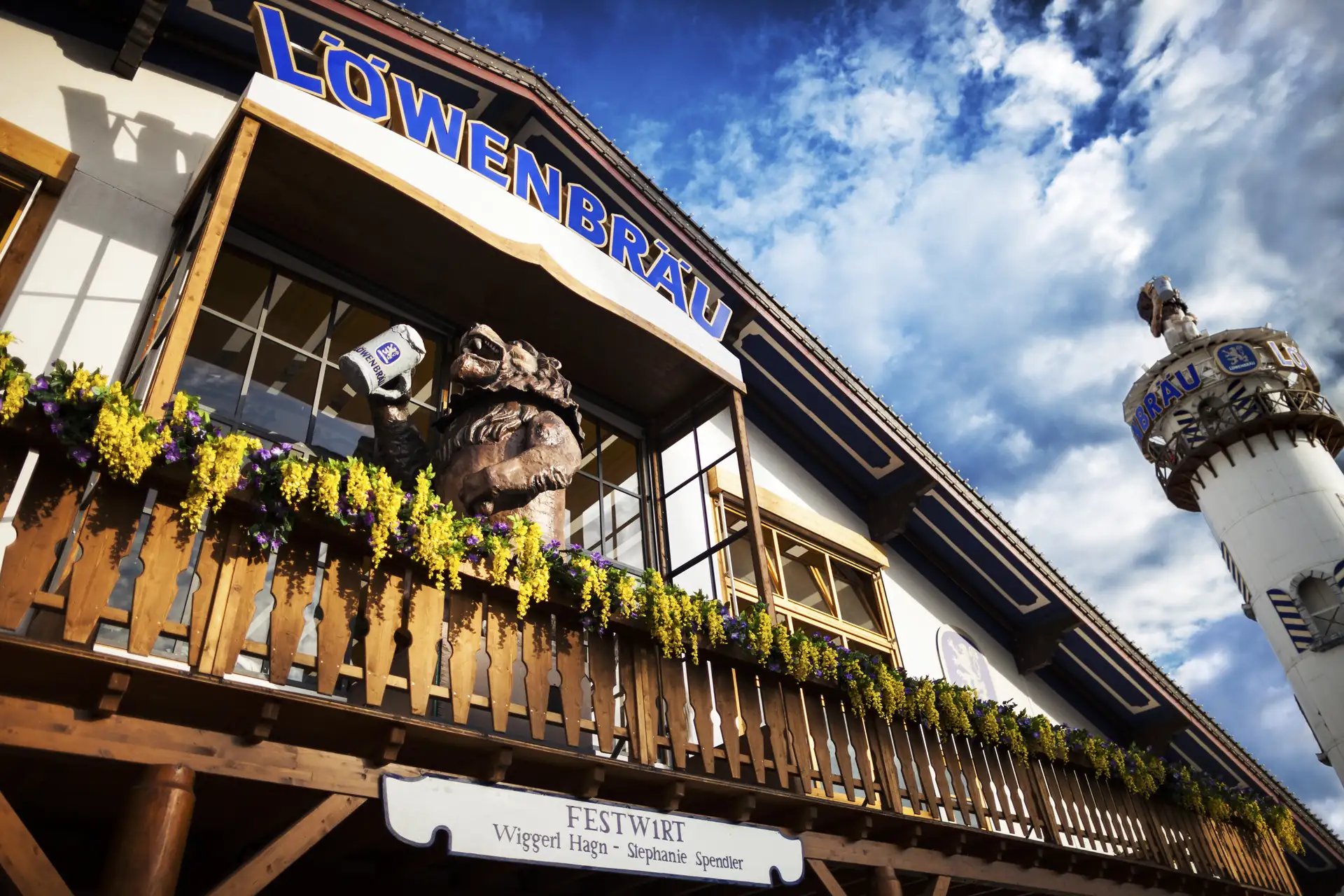 Löwenbräu Festzelt auf dem Münchner Oktoberfest: Löwe über den Eingang des Zeltes in Nahaufnahme und im Hintergrund Löwe auf dem Turm.