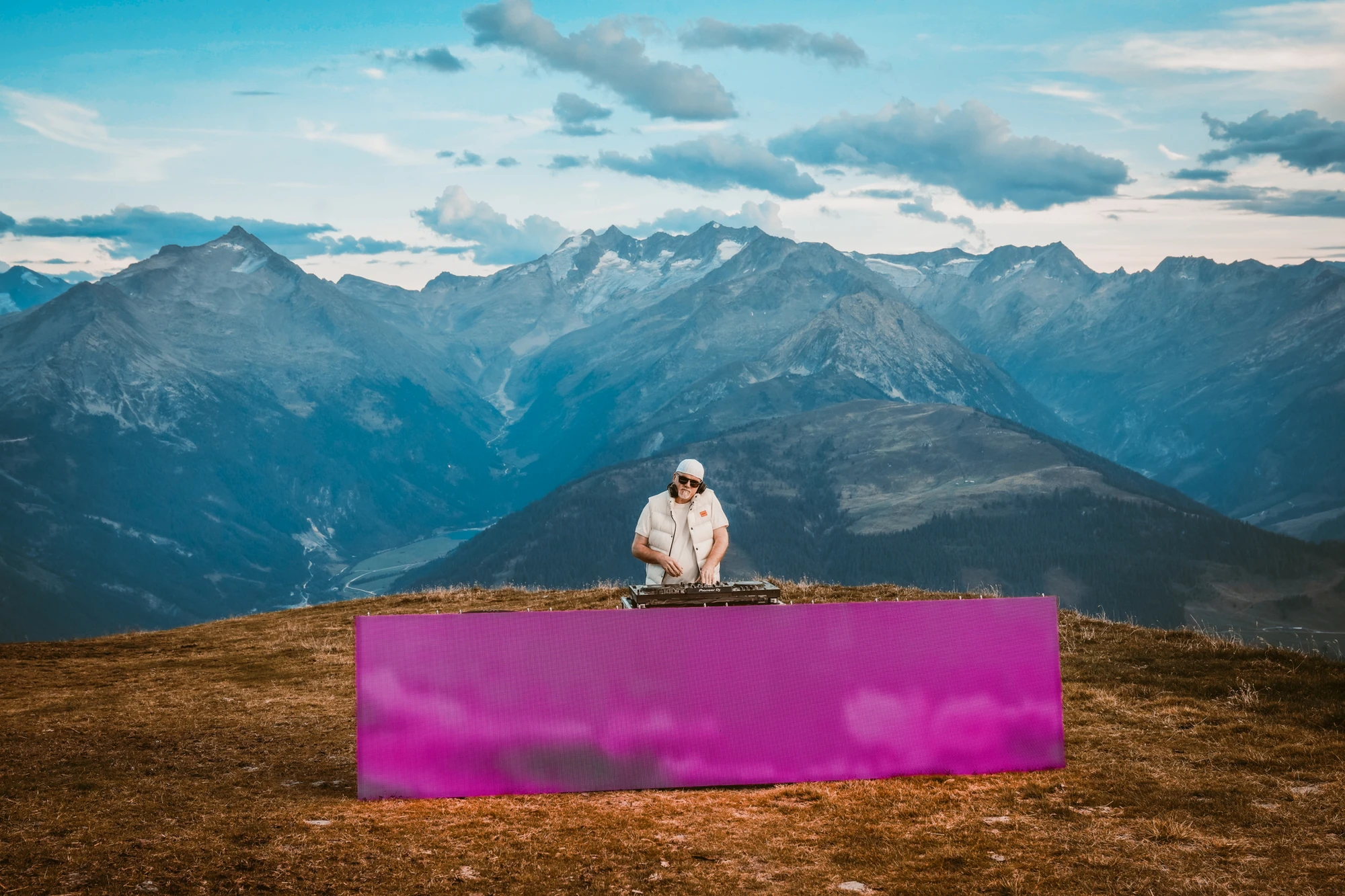 Mountain Mania 2024 - DJ Ötzi Konzert - DJ Ötzi am pinkfarbenen Mischpult vor Bergkulisse