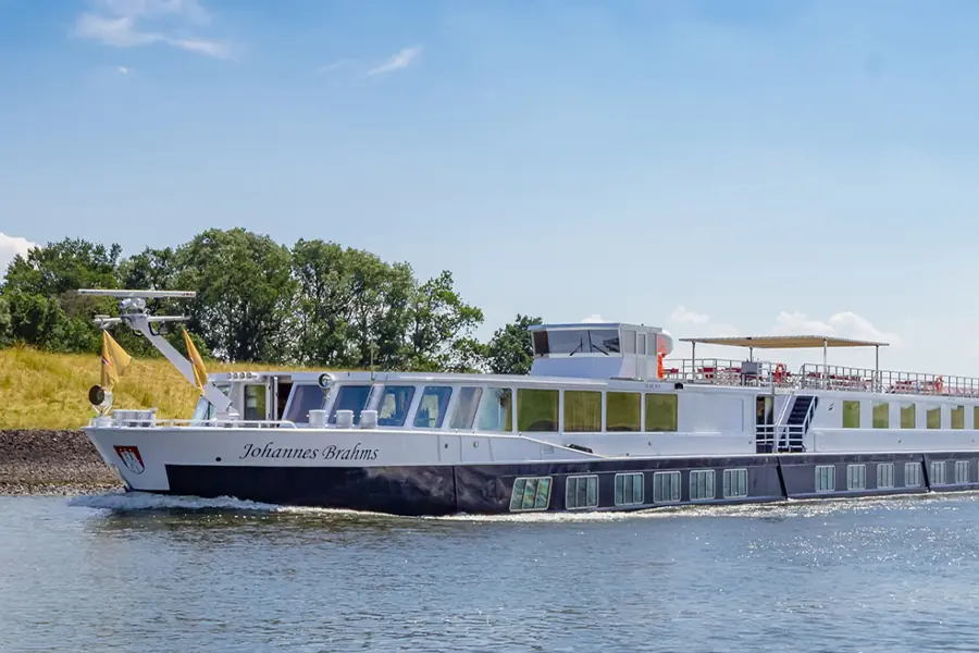 MS Johannes Brahms (blau-weißes Flussschiff) von der Seite während der Fahrt auf dem Wasser im Sommer