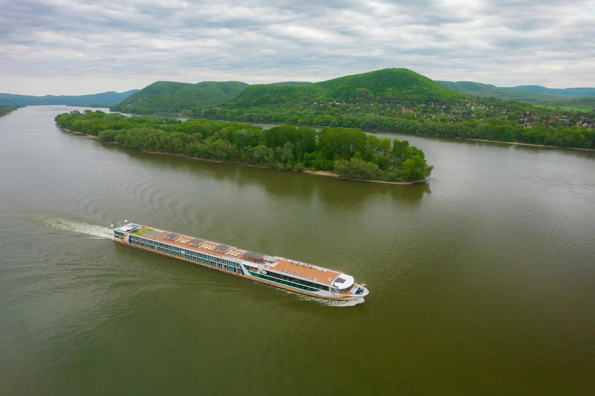 MS VistaSTAR fährt auf der Donau im Hintergrund bewaldete Hügel und Ufer mit Bäumen.