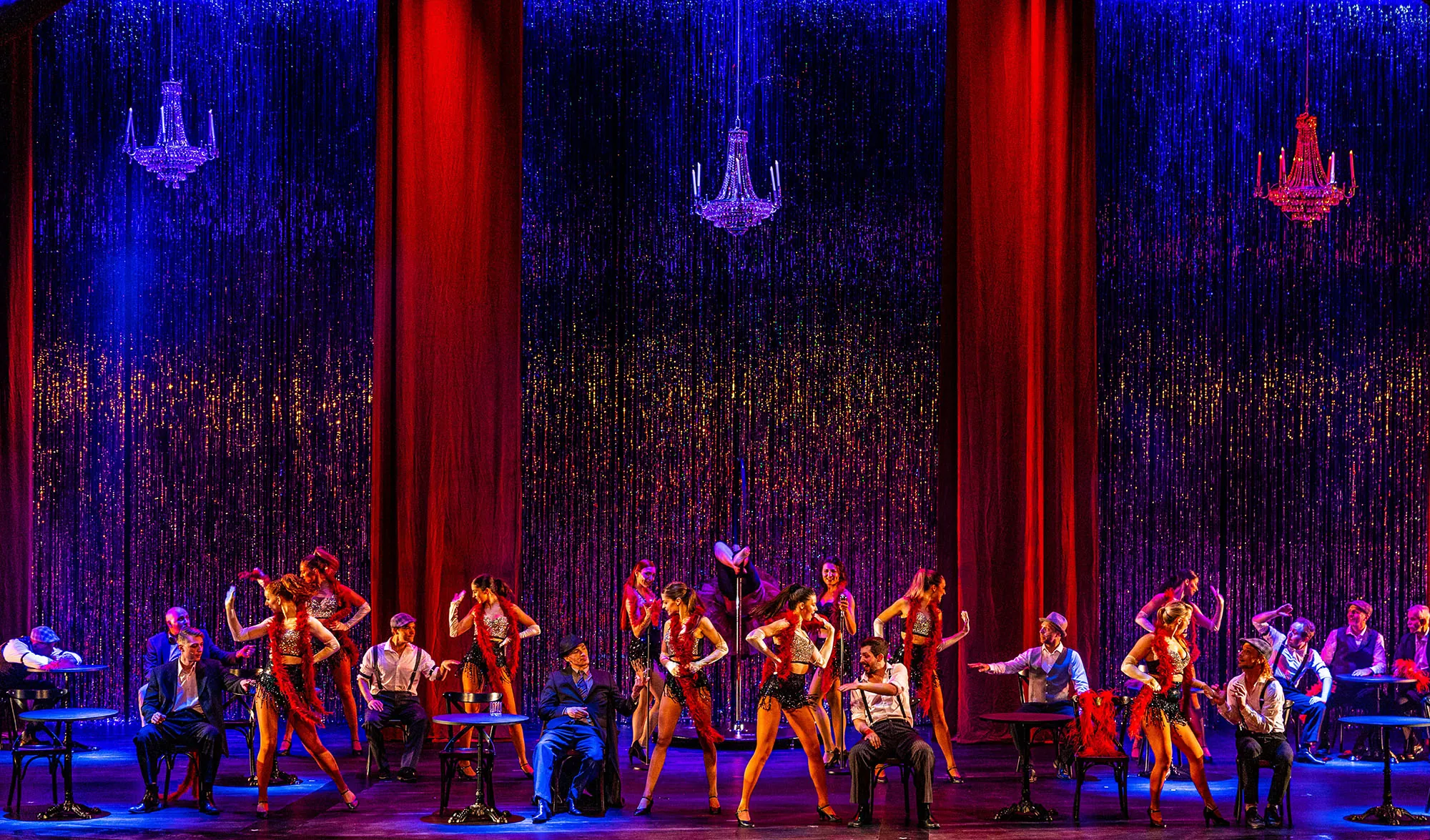 Tänzerische Darbietung im Varieté mit einem funkelnden Vorhang im Hintergrund.