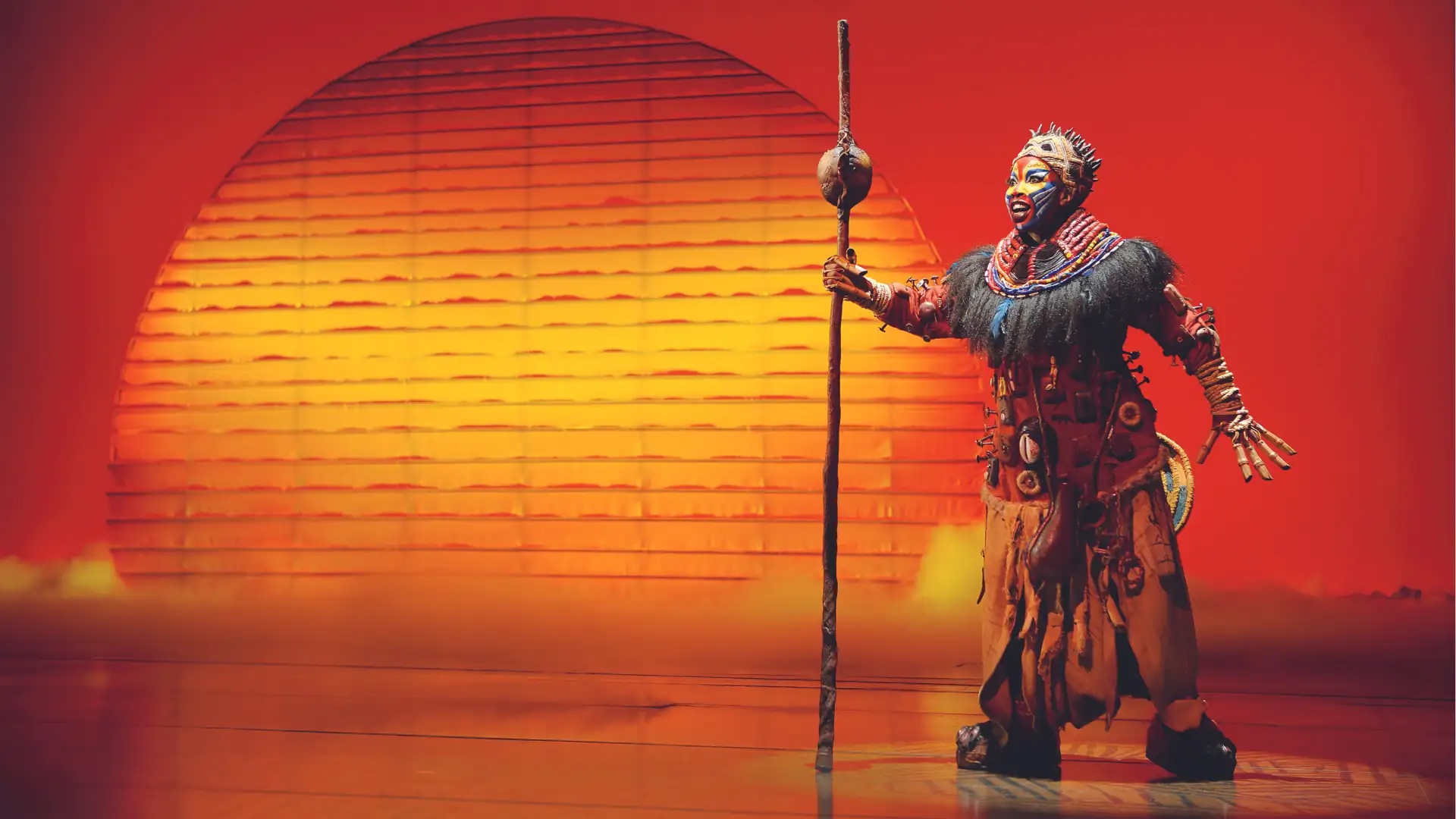 Musicalreisen Symbolbild: Szenenmotiv von Disneys Der König der Löwen – Rafiki vor der aufgehenden Sonne.