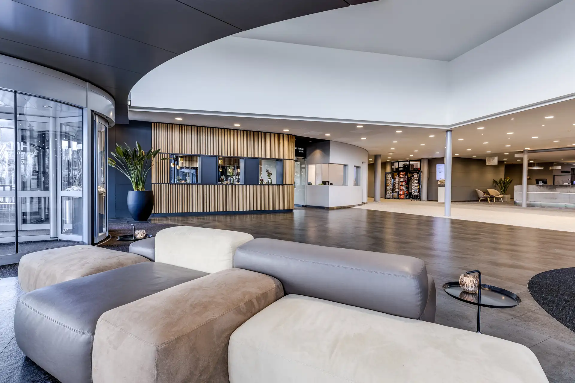Moderne Hotellobby mit grauen und beigen Sofas, großem Fenster, Pflanzen und Holzverkleidung an der Rezeption. mit grauen und beigen Sofas, großem Fenster, Pflanzen und Holzverkleidung an der Rezeption.