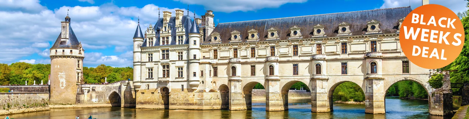 Schloss Chenonceau mit Brückenbogen über den Fluss, Renaissancefassade, Türme und blauer Himmel mit Wolken.