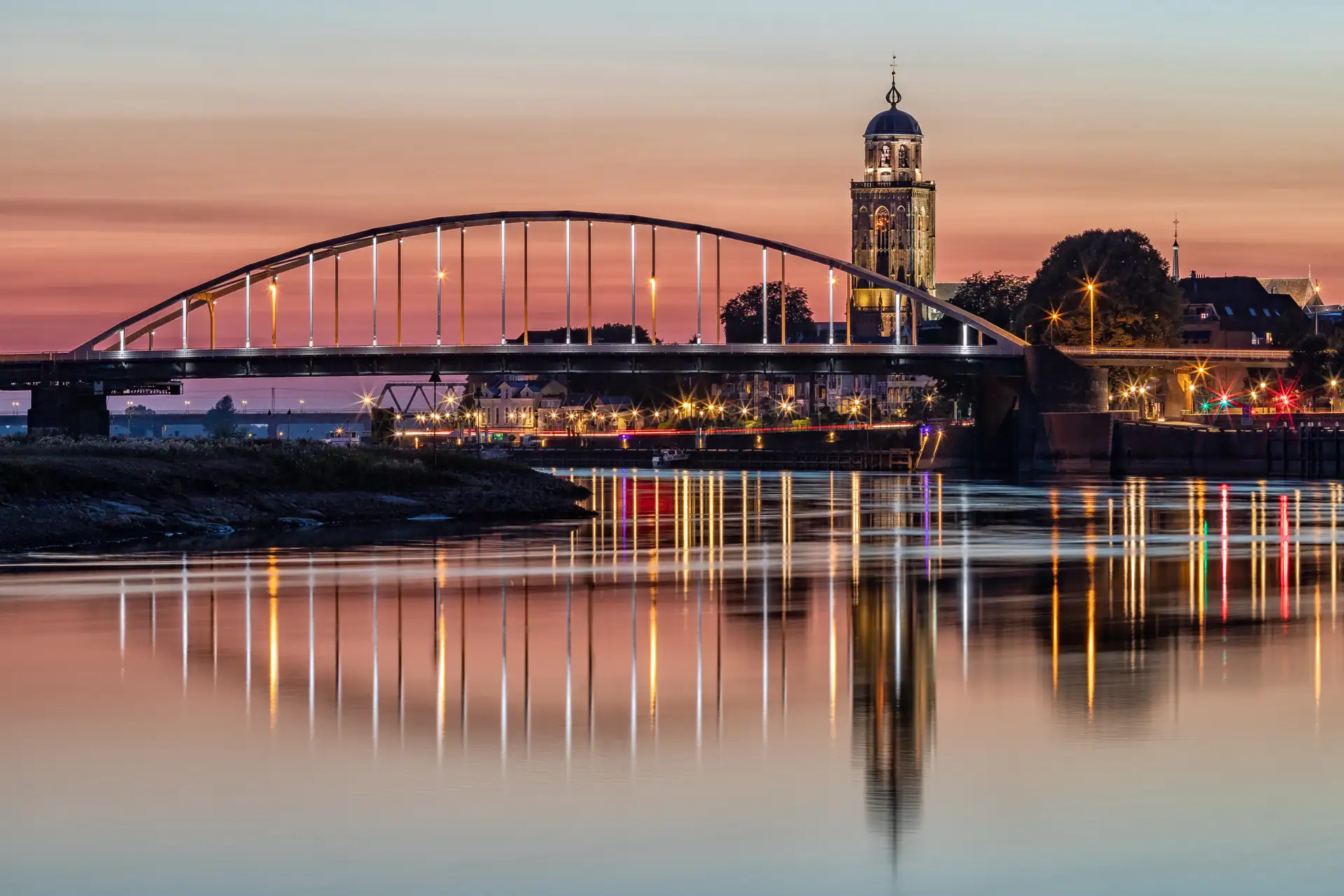Panorama von Deventer bei Sonnenuntergang mit Spiegelung der Lichter und Stadtsilhouette im Wasser