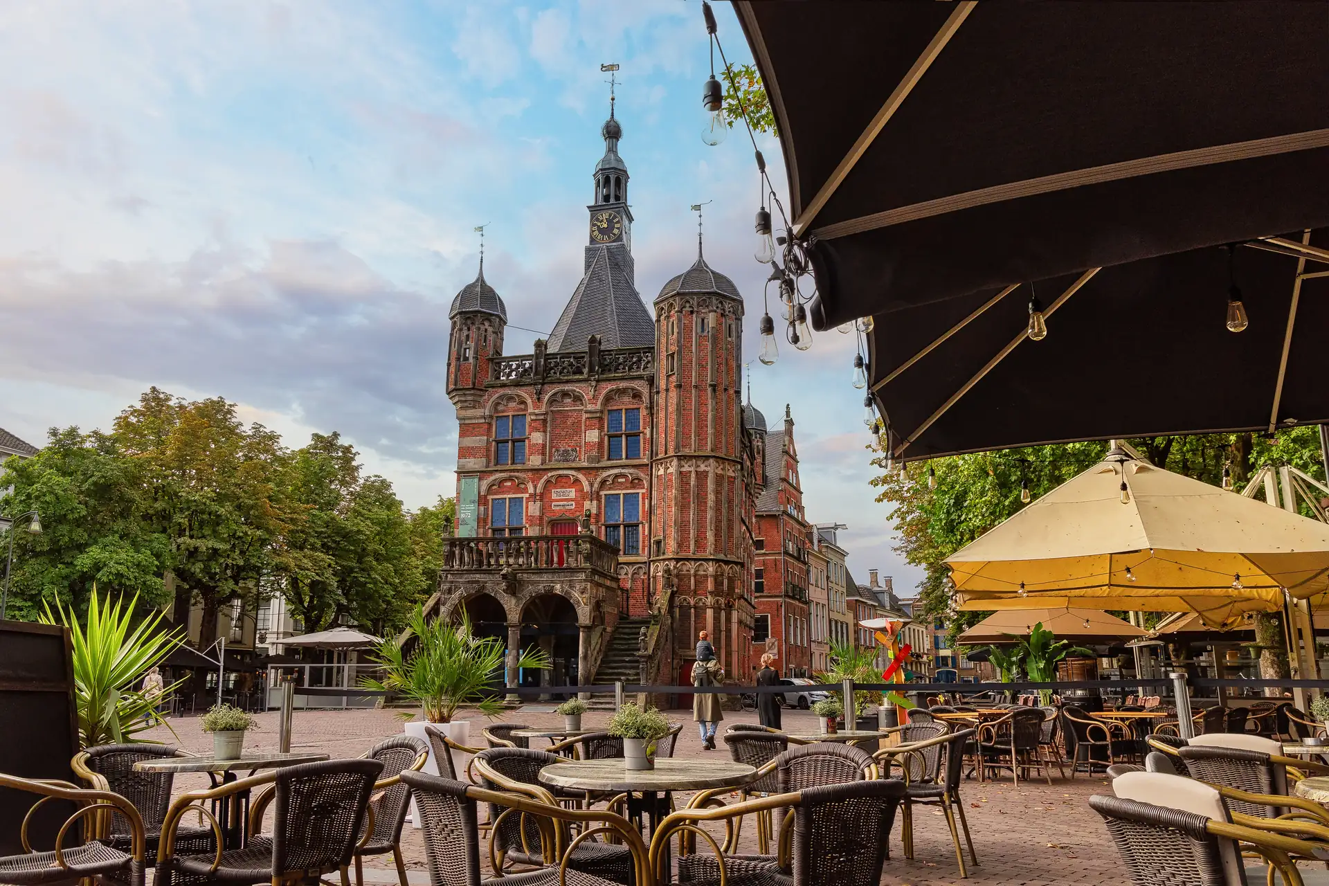 Historisches Haus in der Hansestadt Deventer im Vordergrund Tische eines Straßencafés.