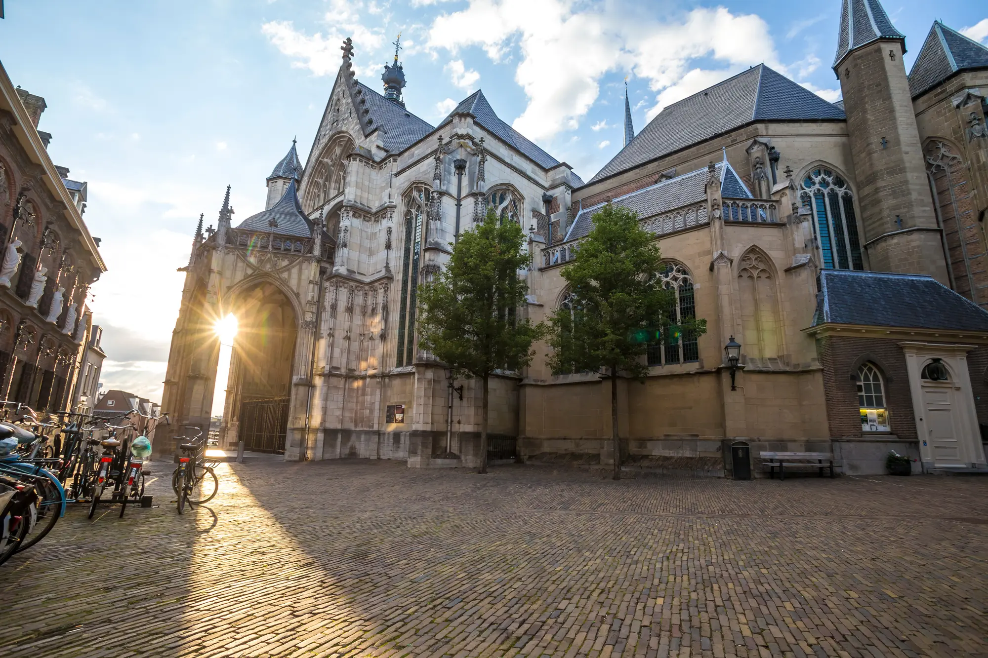 Die Stevenskerk in der Altstadt von Nijmegen bei leichter Abenddämmerung. Das sanfte Licht hebt die imposante Fassade der Kirche hervor, während an der Seite des gegenüberliegenden Gebäudes einige Fahrräder geparkt sind. Die ruhige und charmante Atmosphäre der historischen Stadt wird durch das weiche Dämmerlicht verstärkt.