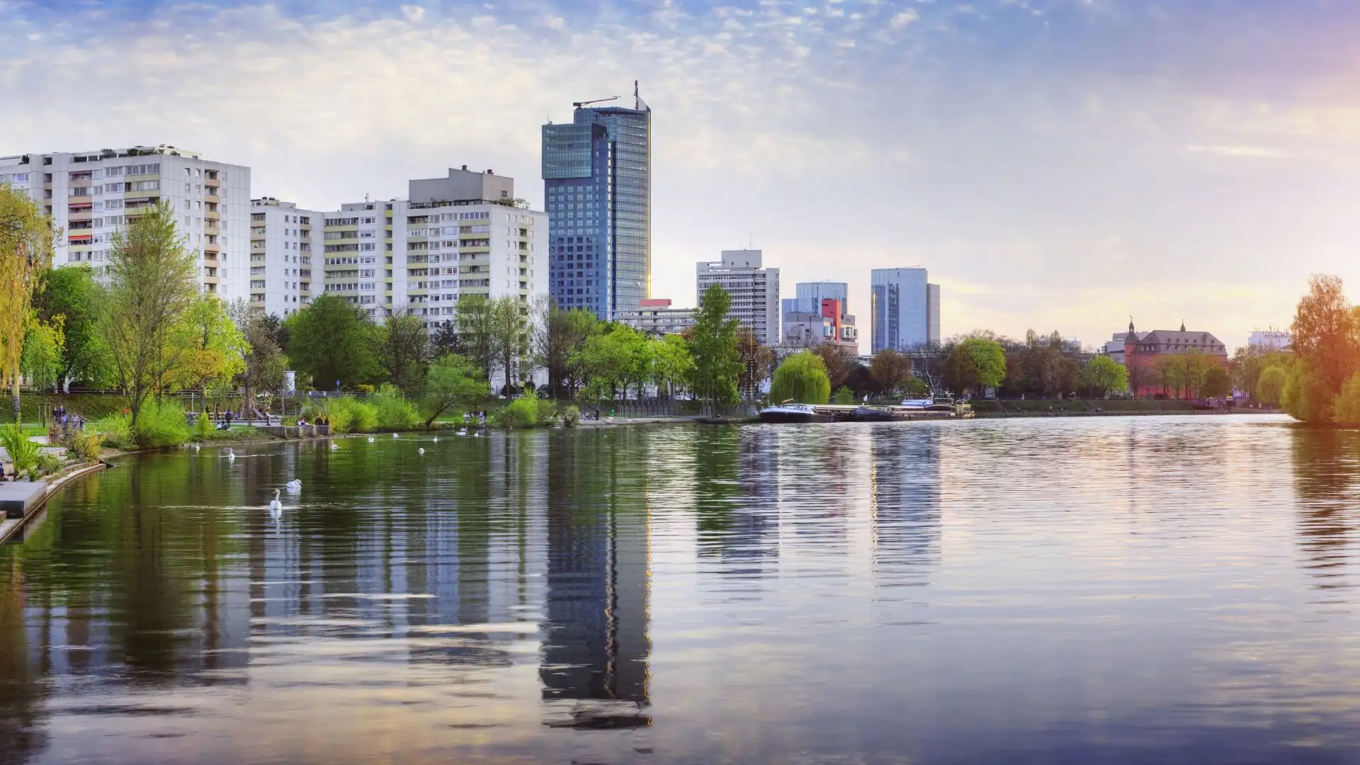 Panoramaansicht eines Stadtsees mit modernen Gebäuden im Hintergrund.