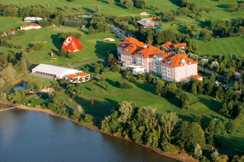 Panoramablick auf Lindner Hotel Wiesensee umgeben von grüner Landschaft mit Uferweg an einem Fluss