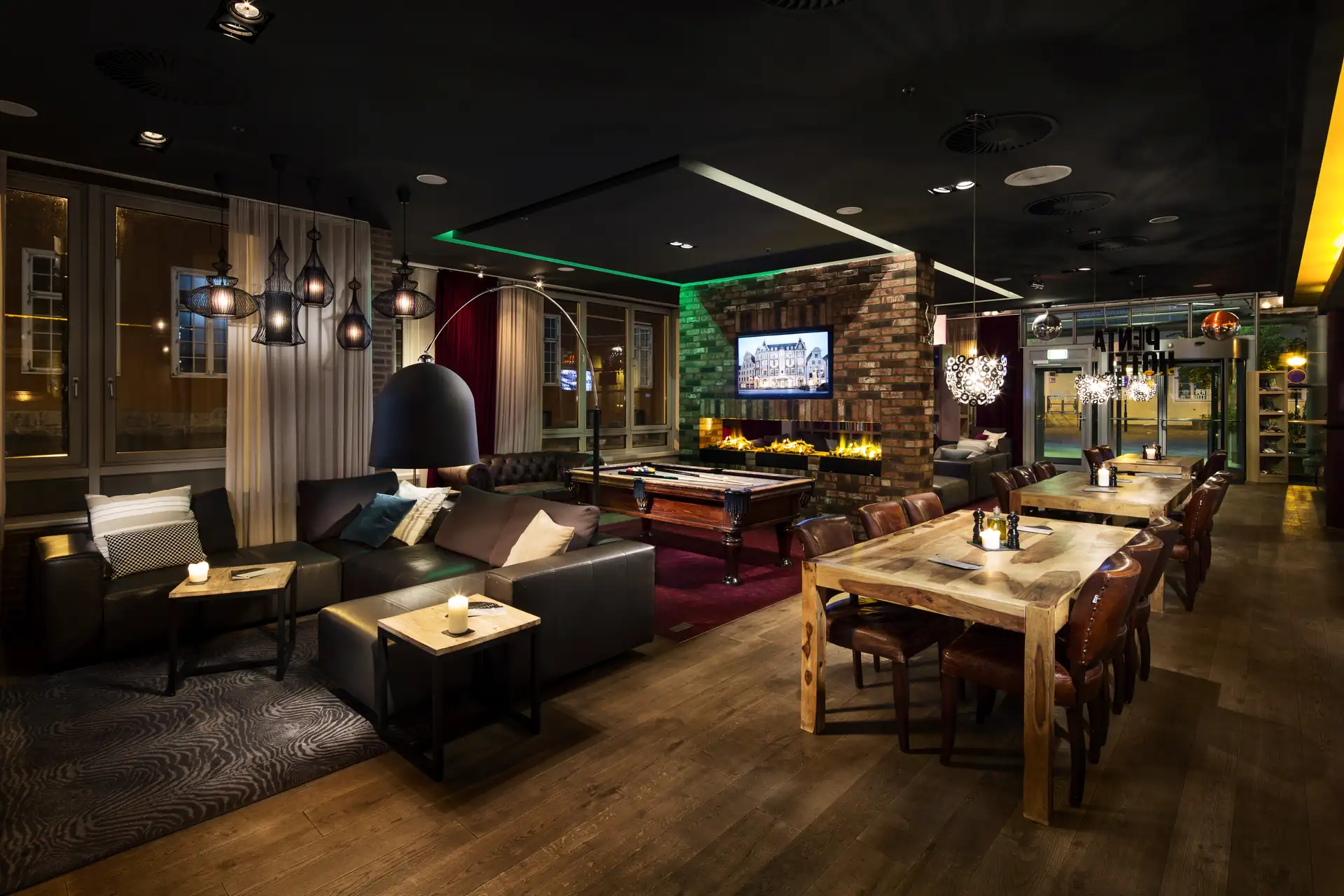 Moderne Lounge im Penta Hotel Rostock mit Sofas, Holztischen, Billardtisch und dekorativer Beleuchtung in warmem Ambiente