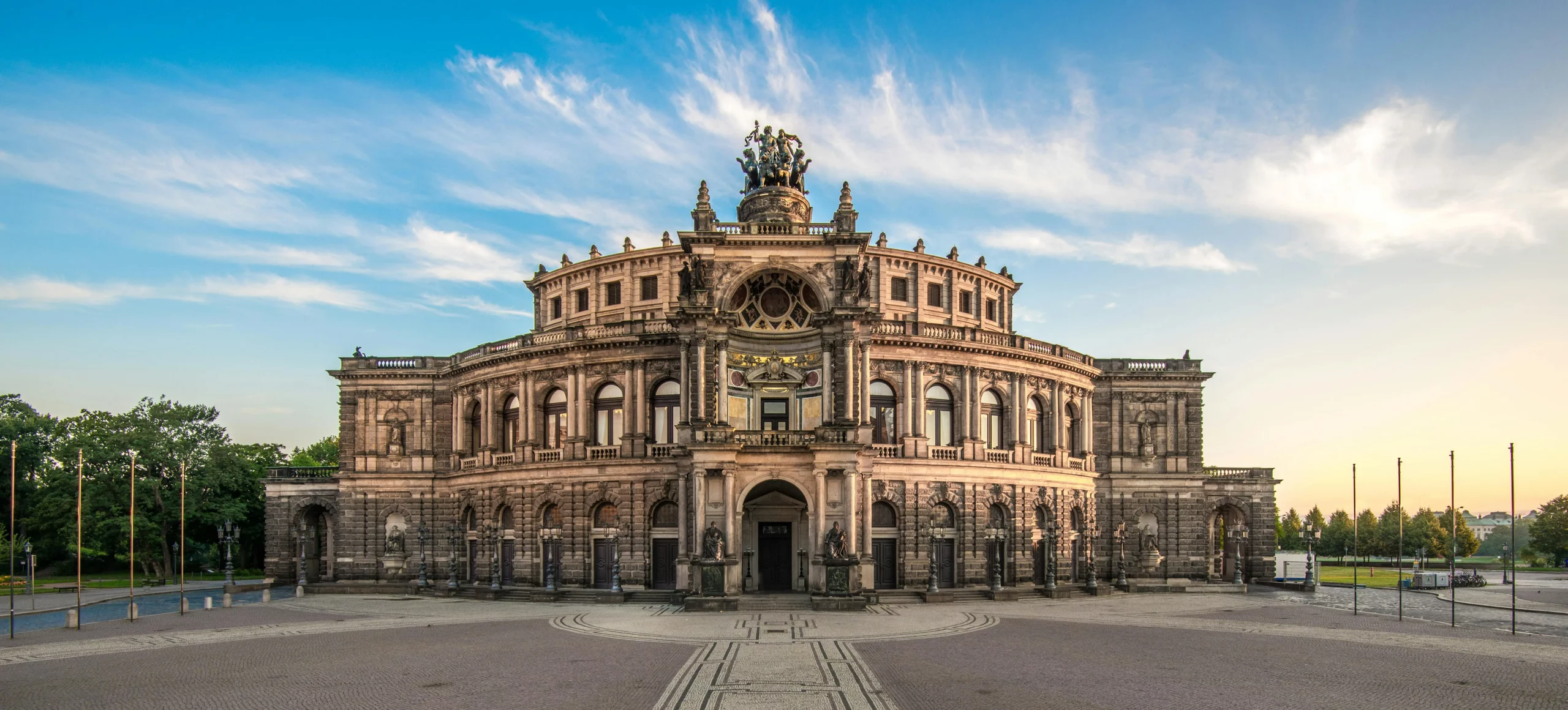 Die Semperoper in Dresden ist eines der bedeutendsten Opernhäuser Deutschlands und ein Meisterwerk der Architektur. Die imposante Fassade der Oper, die im Barockstil erbaut wurde, zeigt eine harmonische Kombination aus kunstvollen Details und einer majestätischen Struktur. Mit ihrem markanten, prunkvollen Eingangsbereich und der Statue an der Spitze des Daches zieht sie Besucher aus der ganzen Welt an. Umgeben von weitläufigen Plätzen und der historischen Altstadt, bietet das Gebäude einen spektakulären Blick auf die Dresdner Skyline. Die Semperoper ist ein Wahrzeichen der Stadt und ein kulturelles Zentrum, das Opern-, Ballette- und Konzertaufführungen von internationalem Rang beherbergt.