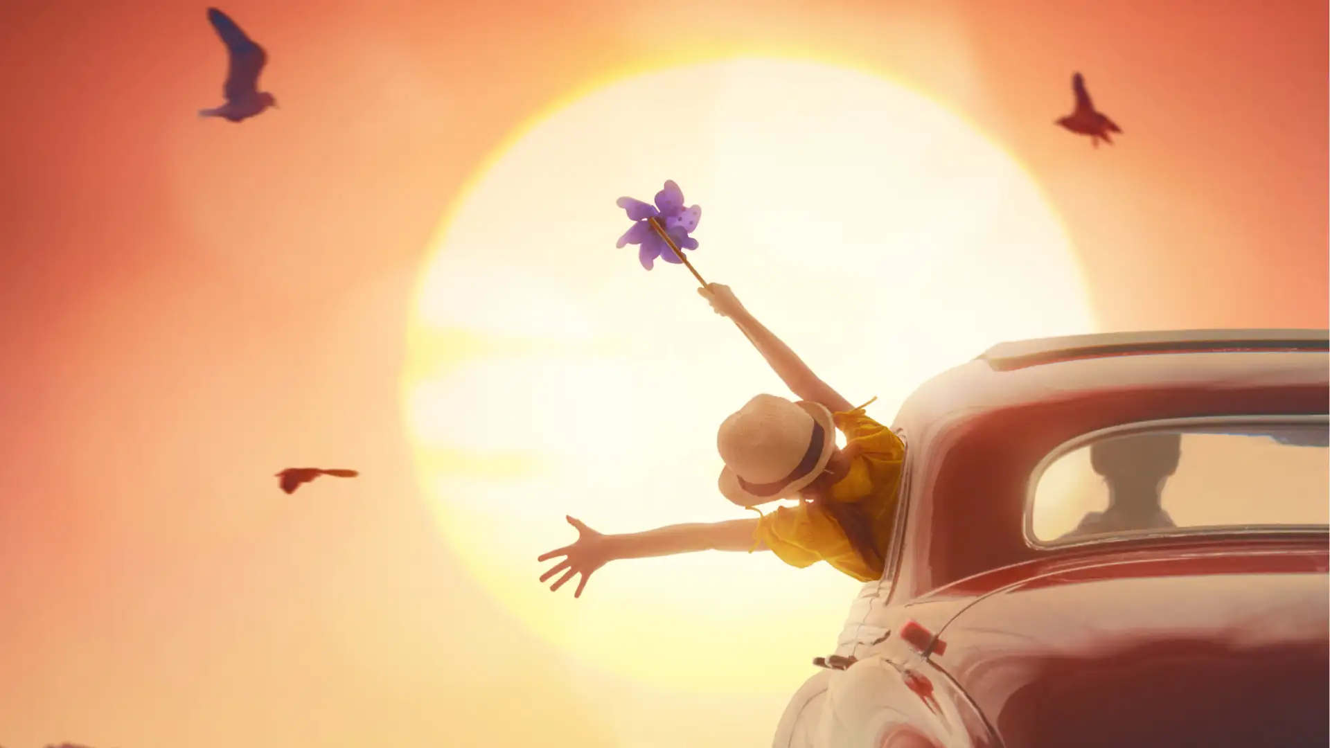 Reisemagazin Symbolbild: Kind hält Windrädchen aus einem fahrenden Auto vor gleißender Sonne.