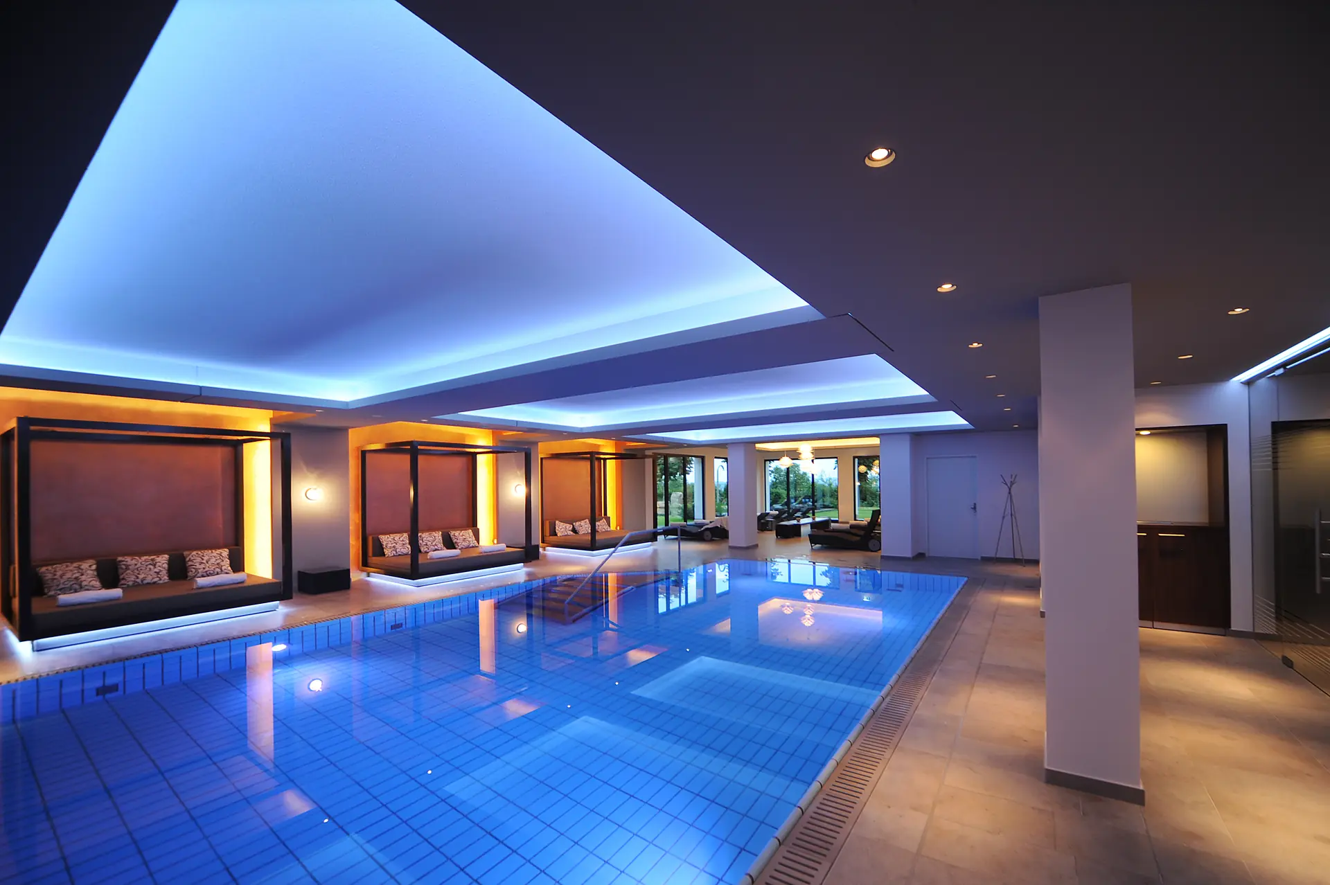 Indoor Pool mit strahlend blauem Wasser und Day Beds am Beckenrand im Schlosshotel