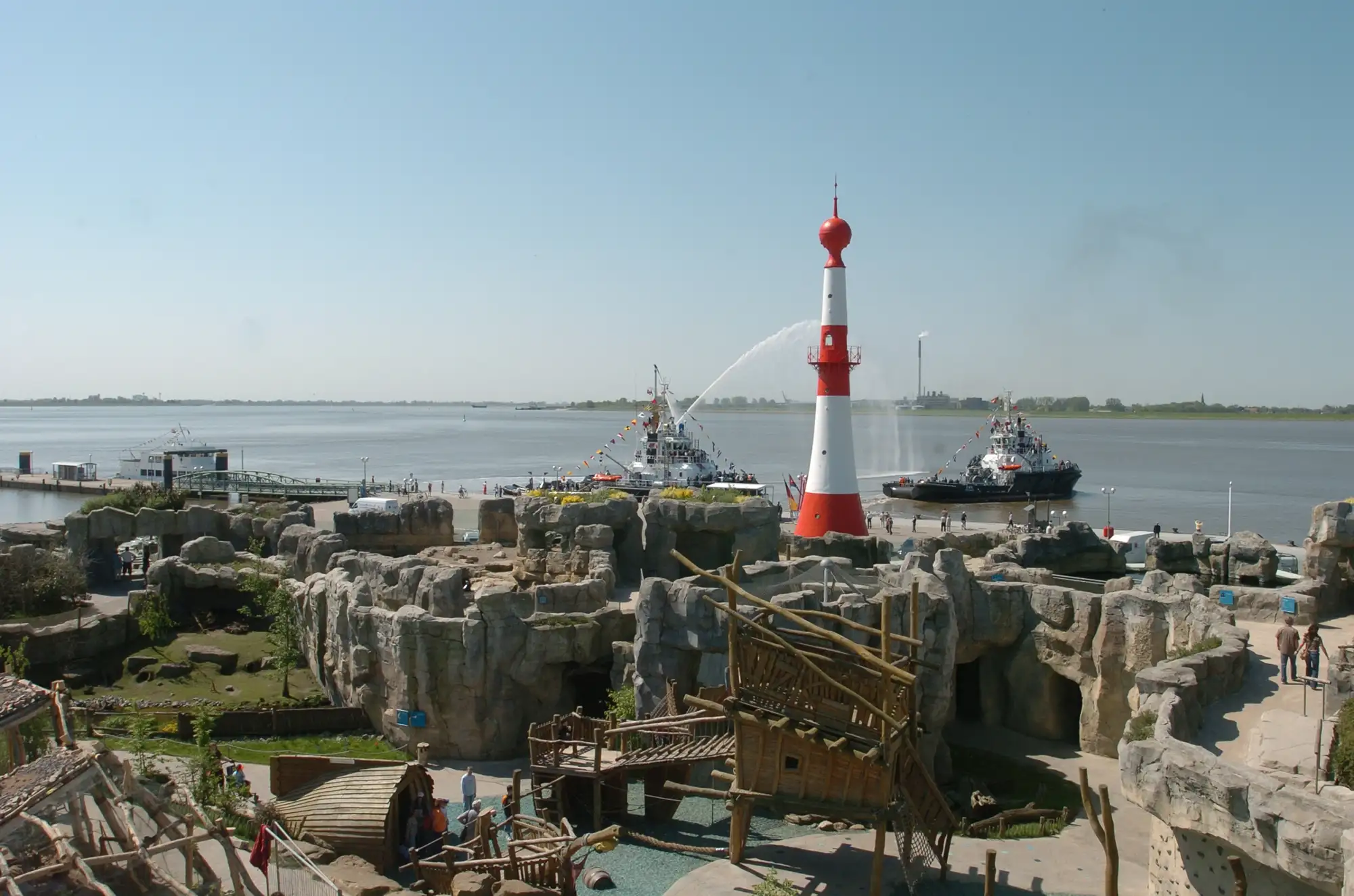 Schiff im Hafen mit bunten Flaggen und Wasserfontänen.