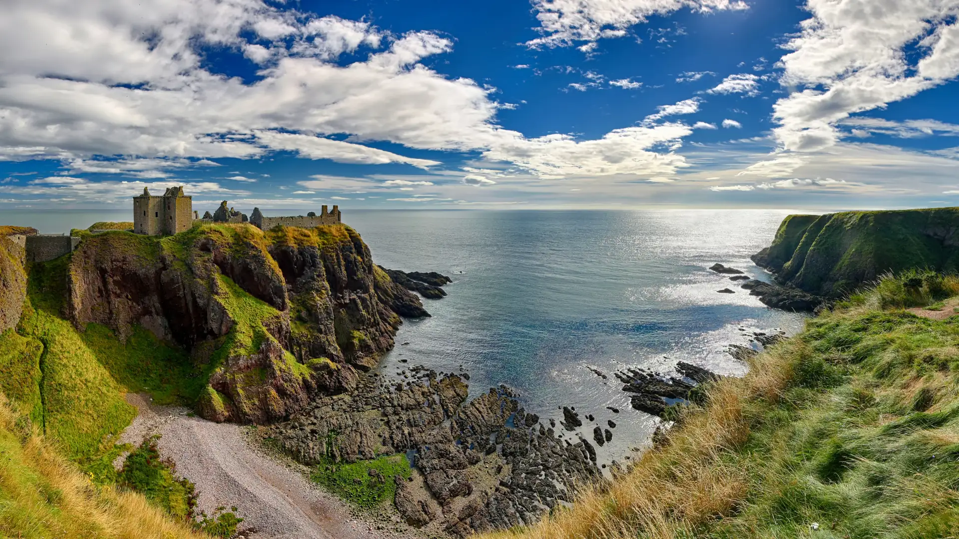 Panoramabild von Dunnottar Castle auf einer felsigen Klippe über dem Meer unter bewölktem Himmel in Schottland