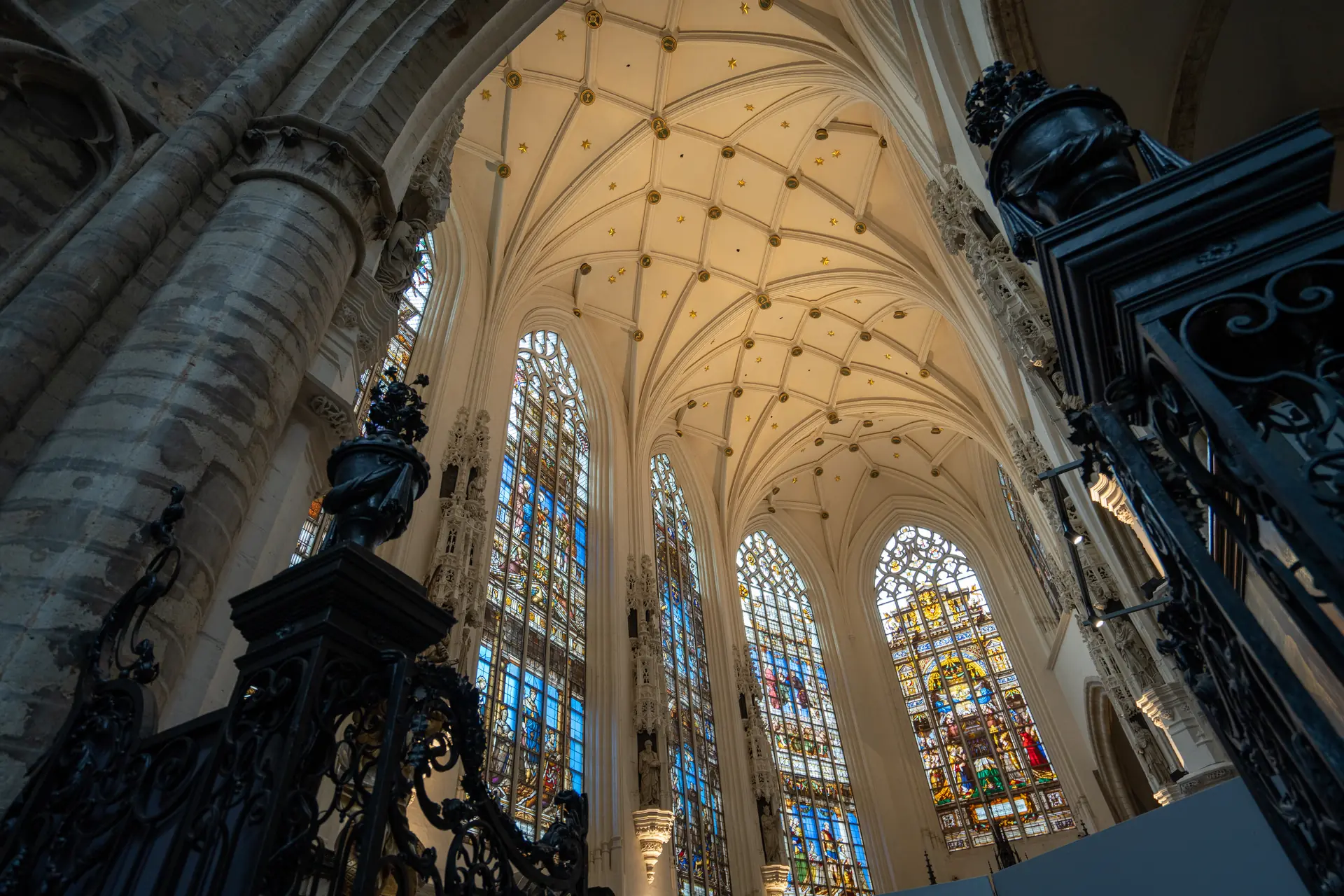 Innenansicht der St. Michael und St. Gudula Kirche, mit beeindruckenden bunten Kirchenfenstern, die farbenfrohes Licht auf die steinernen Wände werfen und eine atmosphärische Stimmung schaffen.