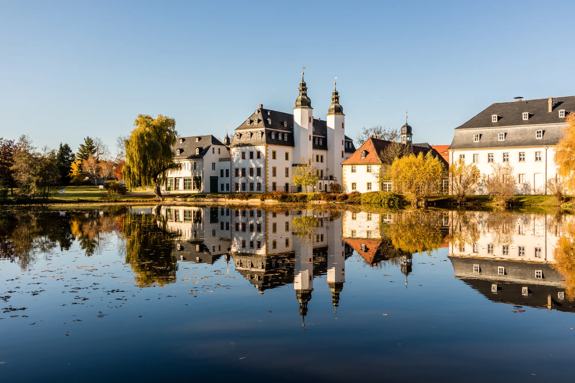 Schloss Blankenhain in der Nähe der Stadt Zwickau spiegelt sich im Wasser bei strahlend blauem Himmel