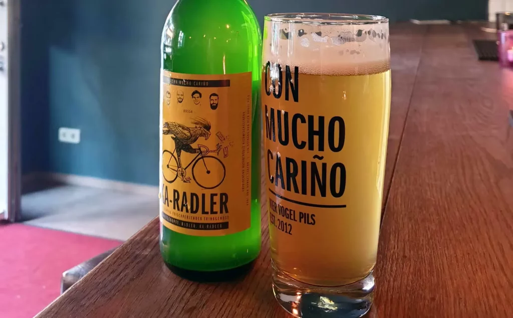 Eine grüne Bierflasche mit Radler-Etikett und ein volles Glas Bier mit Schaum bei der Craft-Bier Führung