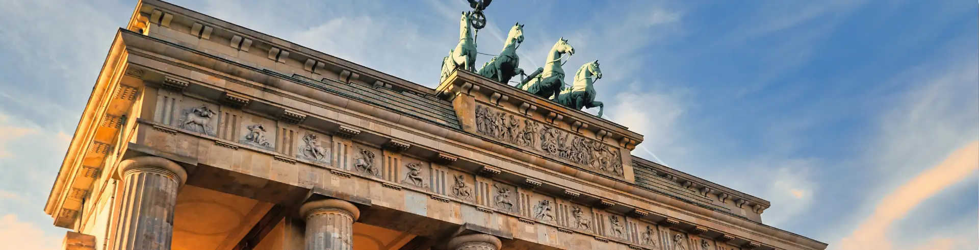 Städtereisen Symbolbild im Bannerformat: Brandenburger Tor in Berlin von schräg unten.