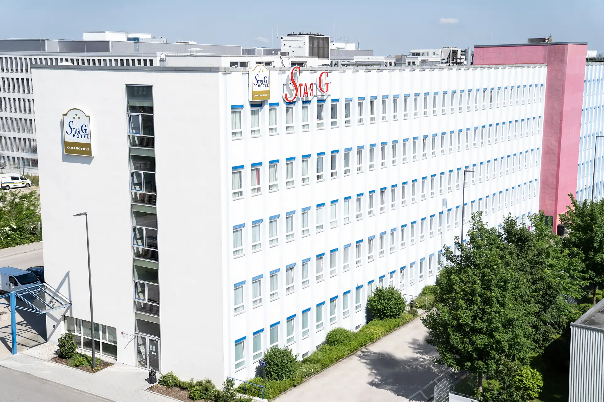 Star G Hotel München Schwabing: Außenansicht der mehrstöckigen, weißen Fassade mit rotem Star G Schriftzug