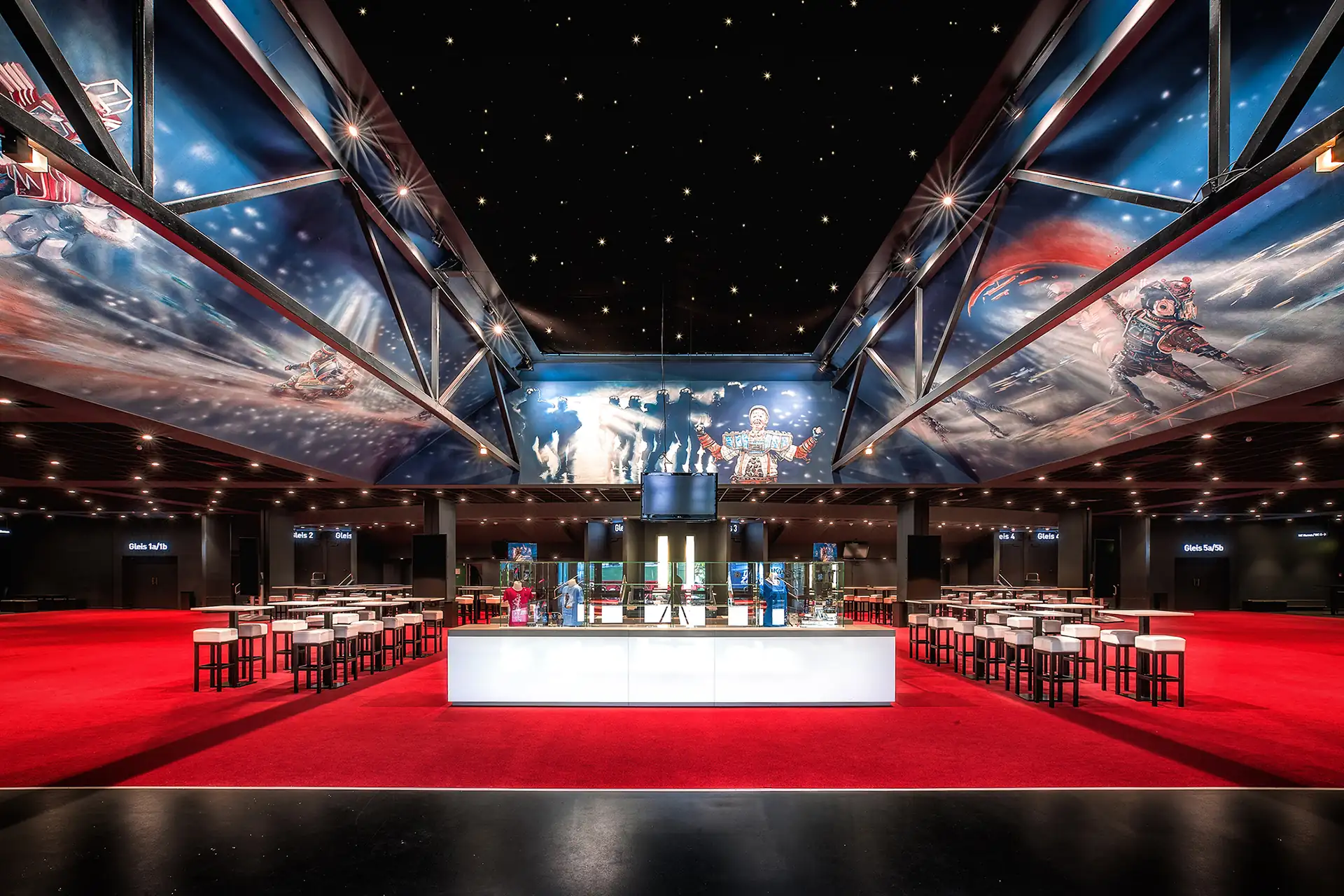 Starlight Express Theater Bochum: Foyer. Theaterfoyer mit Sitzgelegenheiten und Shop sowie Bildern aus der Show an einer Deckenkonstruktion.