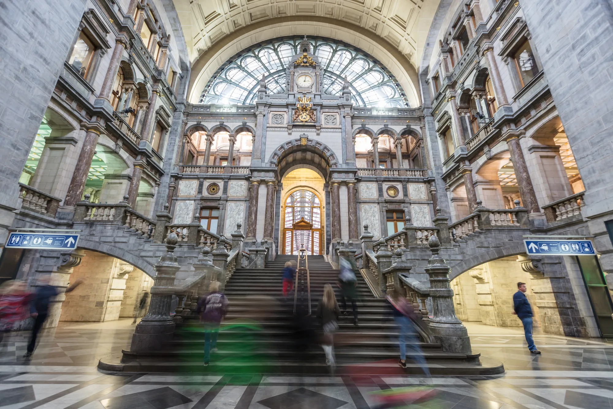 Eingangshalle des Antwerpener Bahnhofs, geprägt von barocker Architektur und goldenen Verzierungen, in der Besucher umherlaufen und die beeindruckende Atmosphäre genießen.