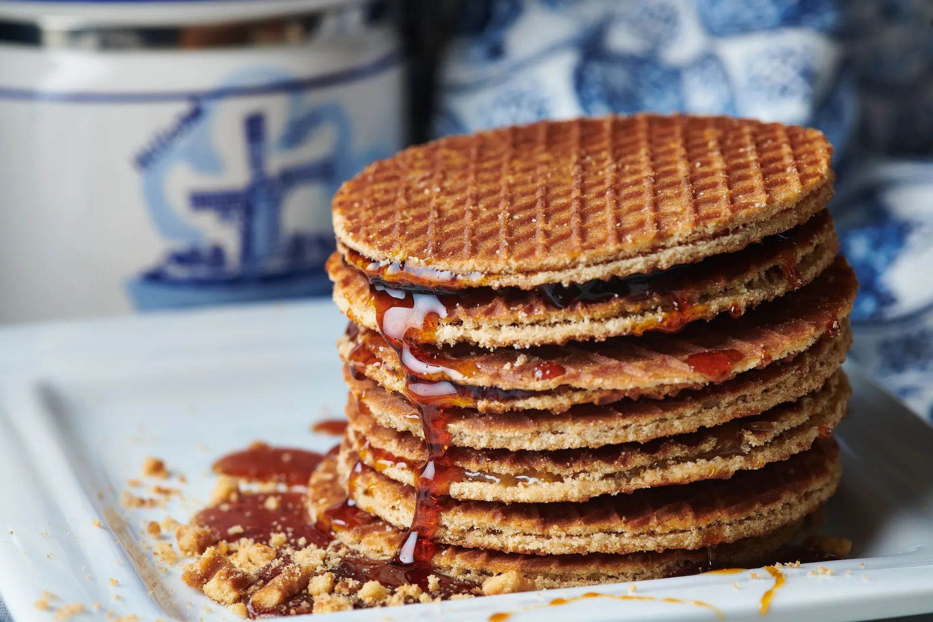 Nahaufnahme einer niederländischen Spezialität, der Stroopwafel, die aus zwei dünnen Waffeln besteht und mit süßem Sirup gefüllt ist. Die Waffeln sind goldbraun und knusprig, während der Sirup verführerisch zwischen den Schichten hervorquillt, was den köstlichen Anblick unterstreicht.