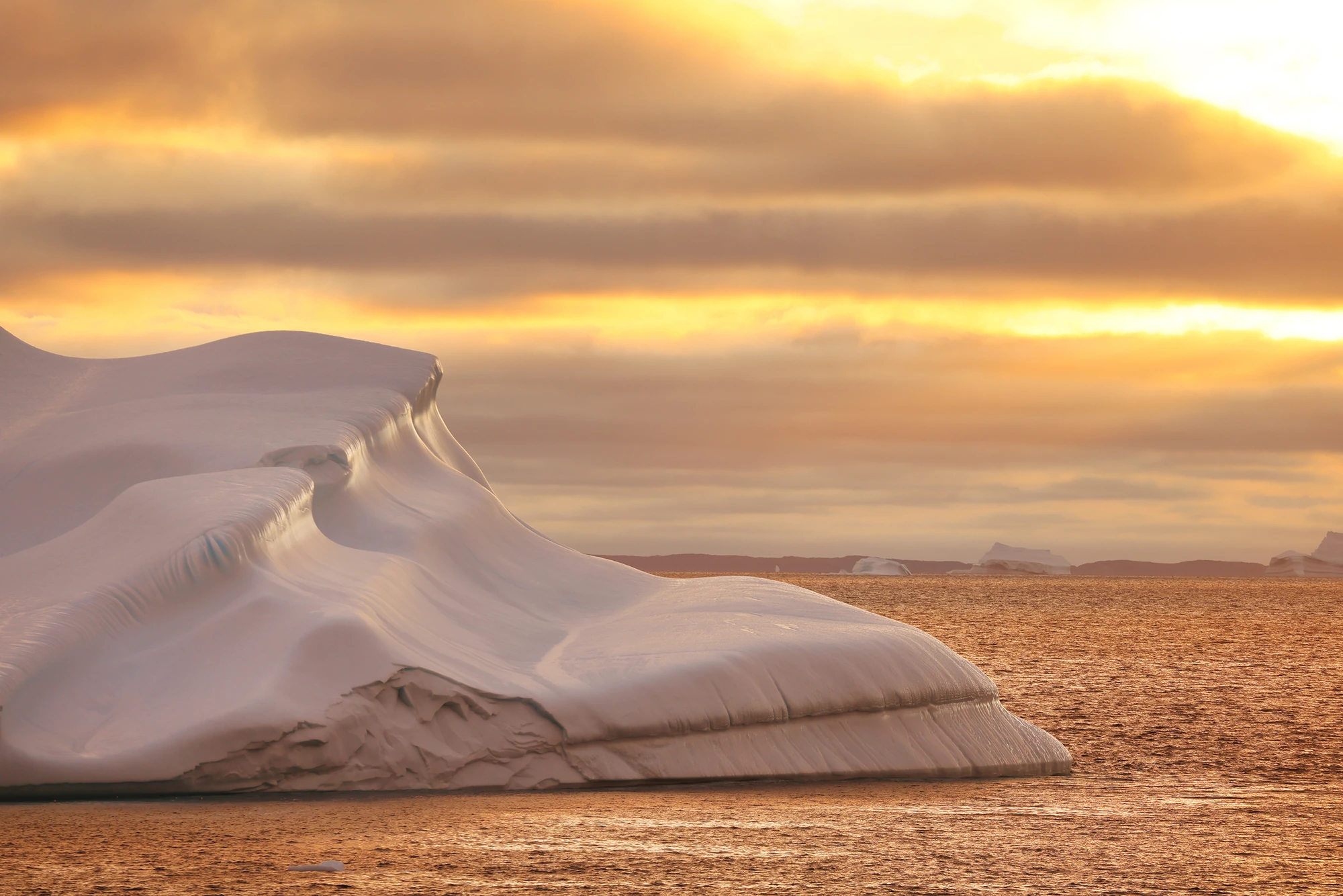 Ein majestätischer Eisberg bei Sonnenuntergang über dem Wasser.