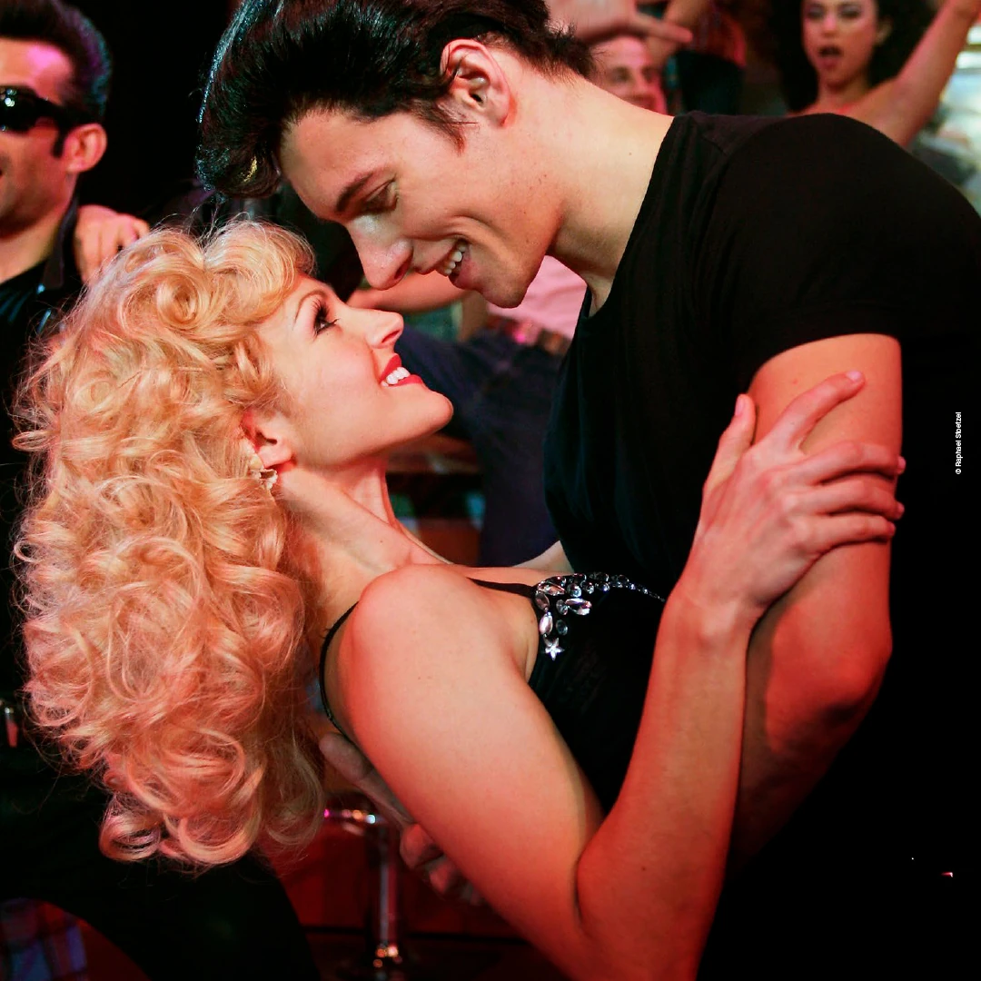 Sandy und Danny tanzen eng zusammen und lÀcheln sich an