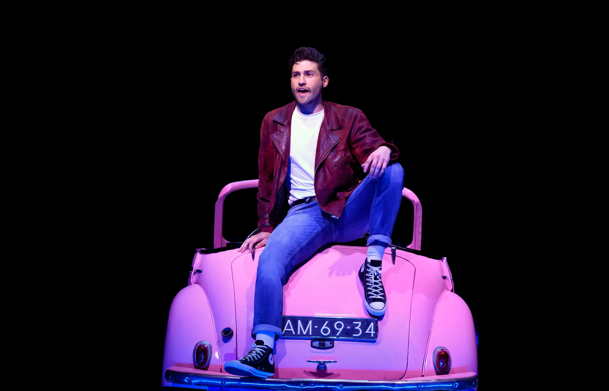 Ein Schauspieler von den Burger Palace Boys sitzt auf rosa Auto