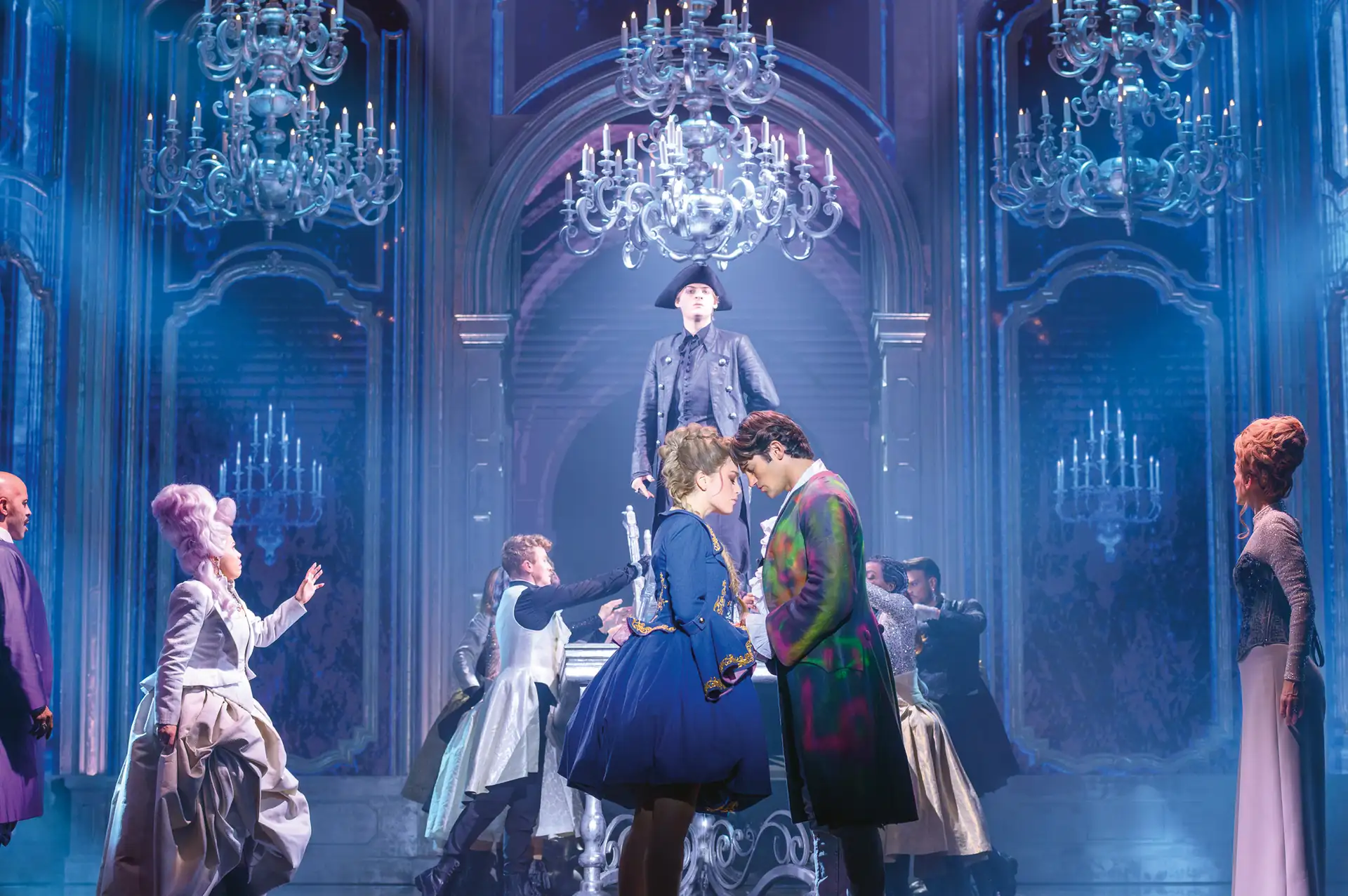 Maria Theresia Musical Szenenfoto: ersonen in historischer Kleidung in einem prunkvollen Saal mit Kronleuchtern, zwei Personen stehen sich nahe gegenüber, andere umgeben sie.
