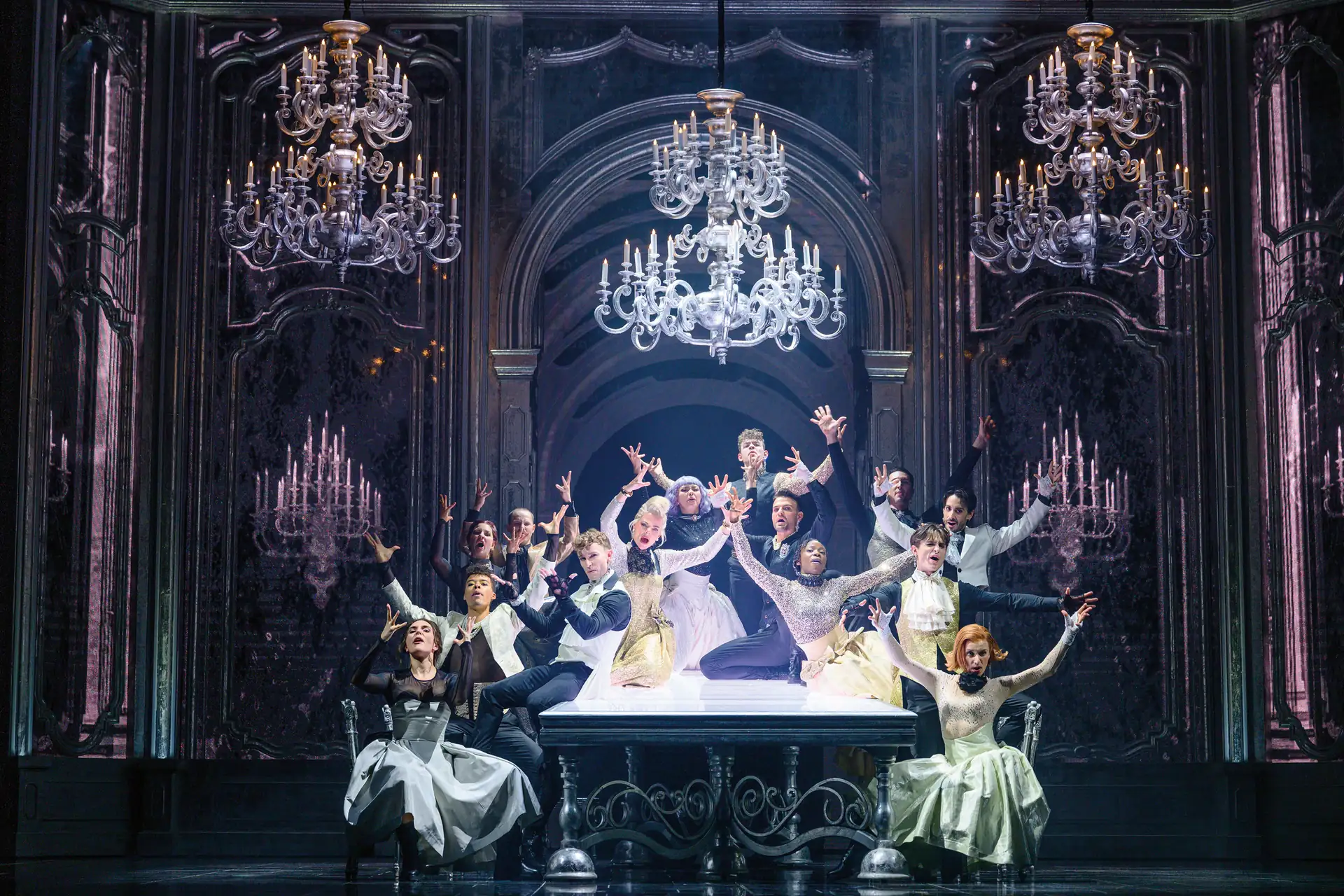 Maria Theresia Musical Szenenfoto: Tanzende Personen in historischer Kleidung auf einer Bühne mit großen Kronleuchtern und verzierten Wänden im Hintergrund.