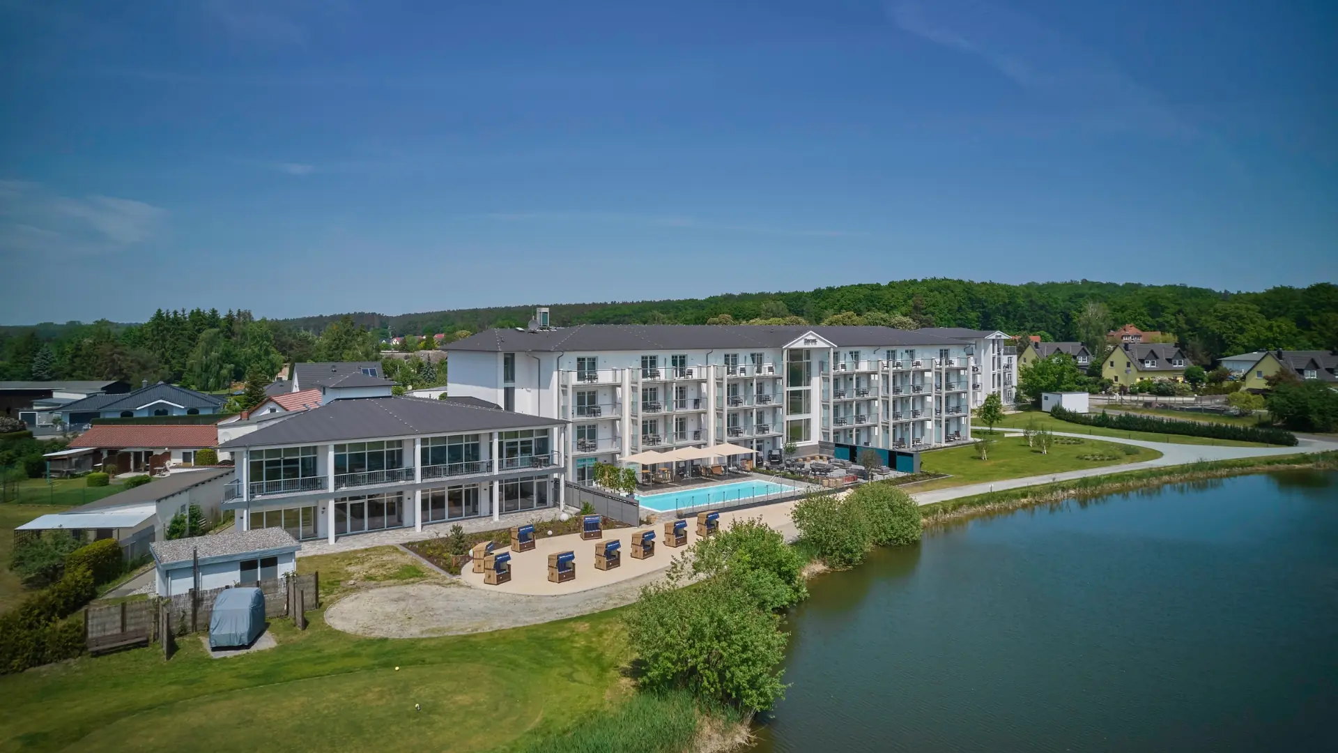 Dorint Resort Baltic Hills Usedom, Außenansicht mit Pool, Strandkörben und Seeufer