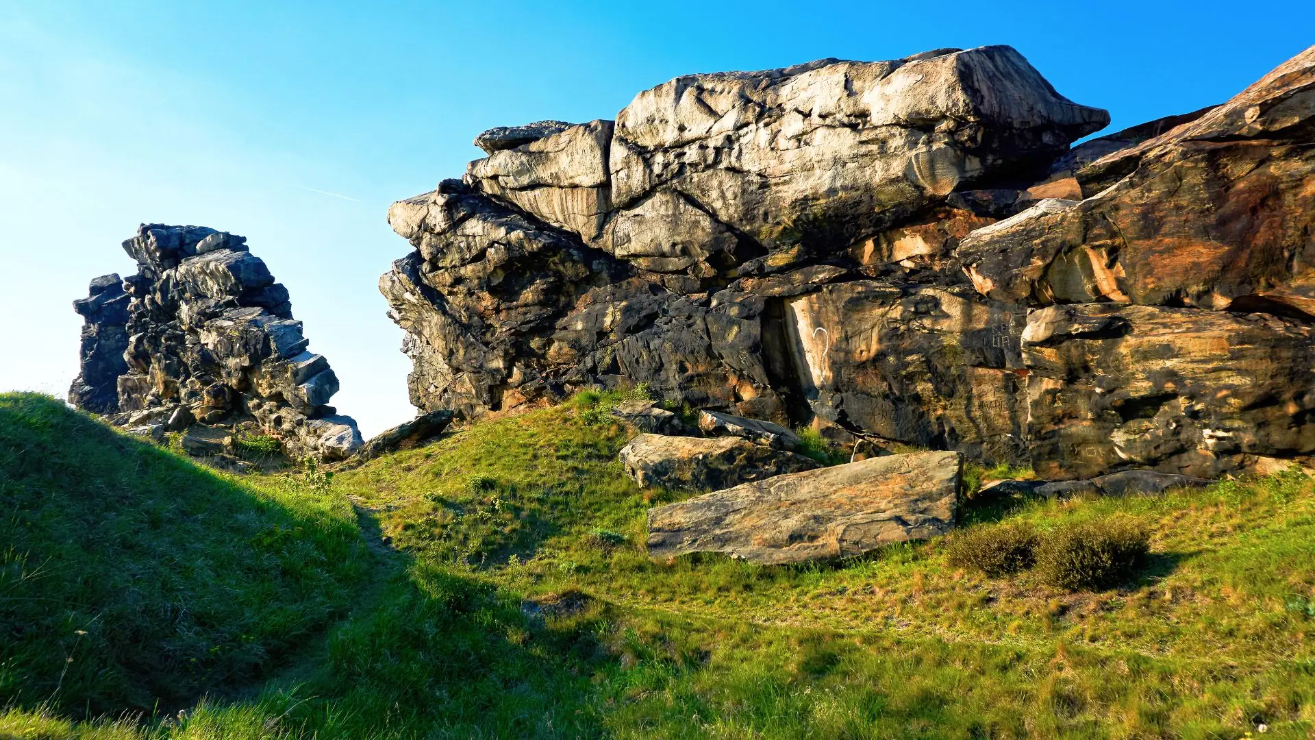 Felsformation der Teufelsmauer bei Quedlinburg mit markanten, zerklüfteten Sandsteinfelsen und grünem Gras im Vordergrund.