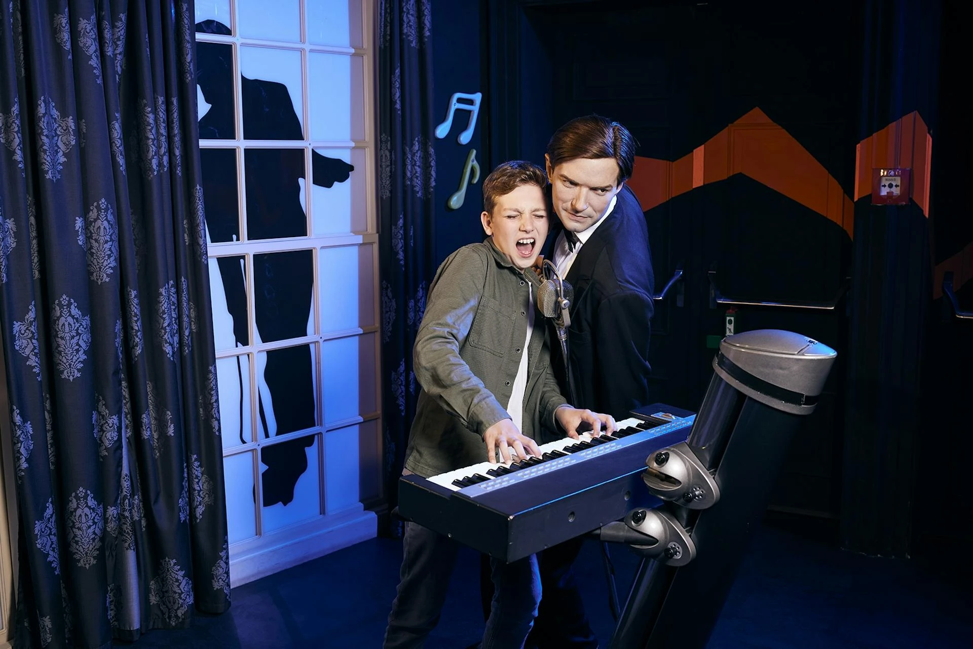 Madame Tussauds Wien - junger Besucher singt neben jungen Falco am Piano