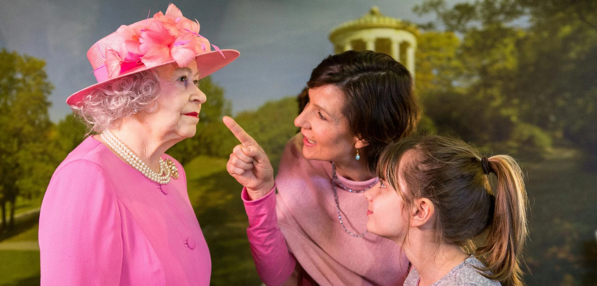 Frau mit Kind zeigt auf die Wachsfigur von der verstorbenen Queen Elizabeth