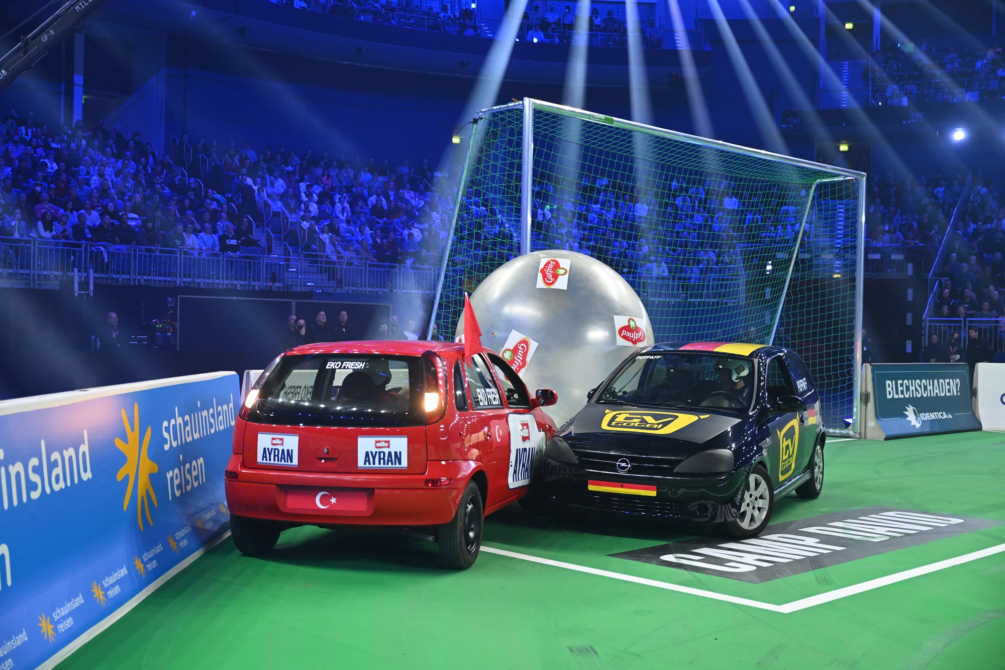 Zwei Autos spielen Fußball in einer Arena mit Publikum.