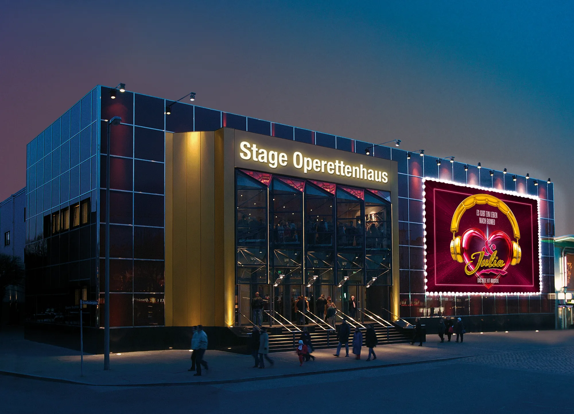 Das Stage Operettenhaus ist in der Abenddämmerung beleuchtet und zeigt ein farbenfrohes Zelt für das Musical „Julia“, vor dem sich viele Menschen versammeln.